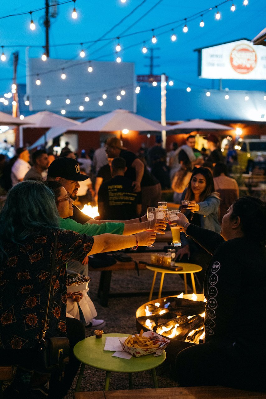 A group of people performing a cheers around a table in the evening