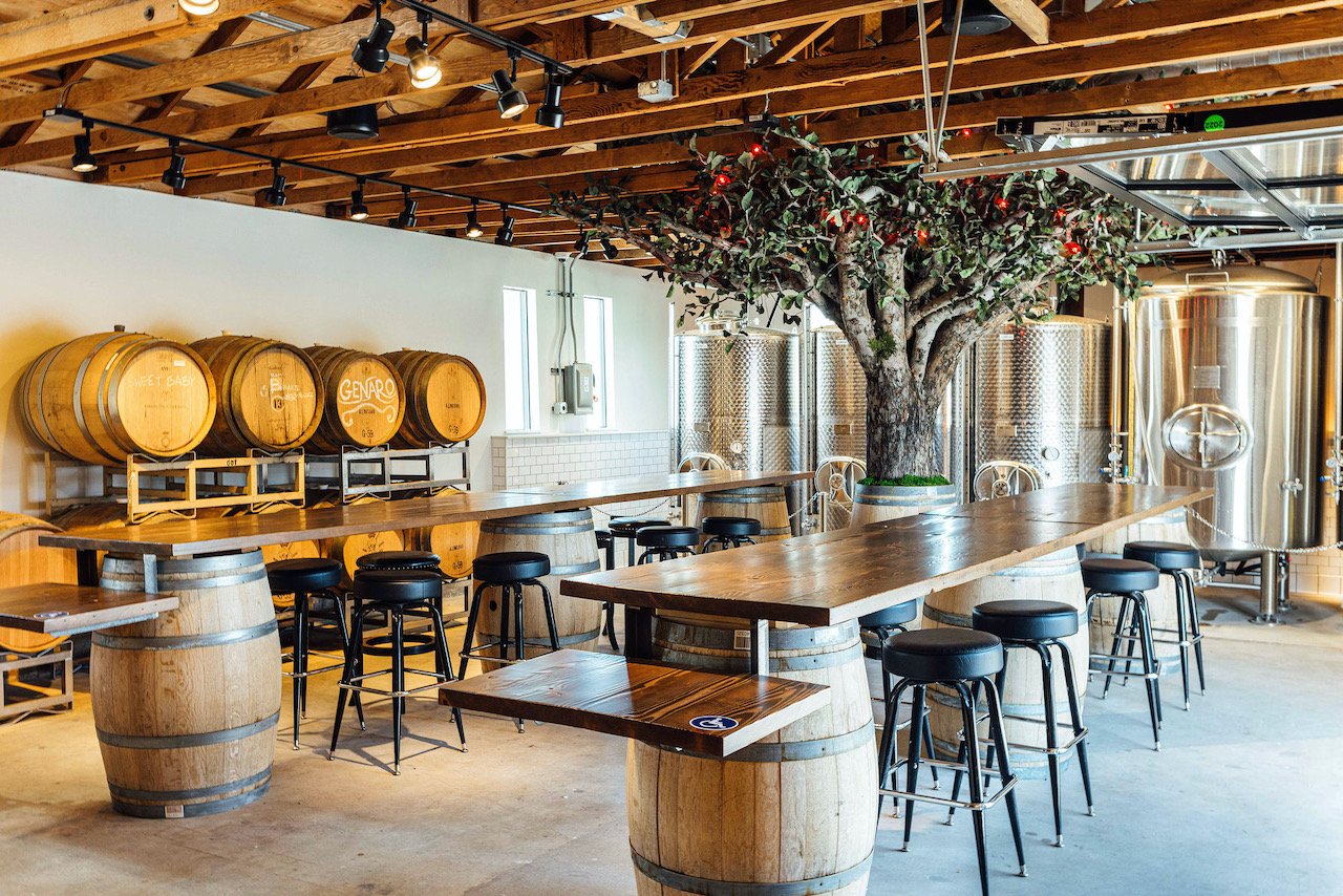 An empty cider house with the tree, barrels, and tables