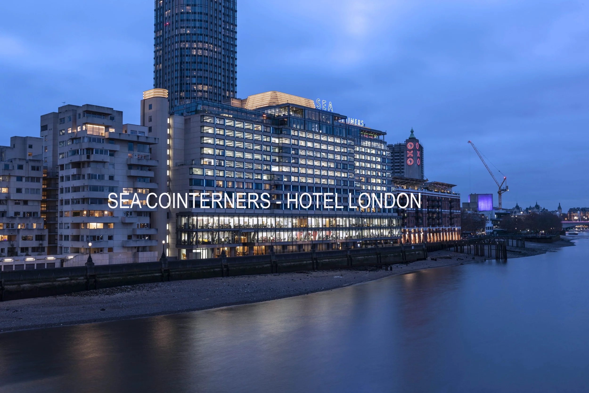 Sea Containers London exterior captured at twilight, showcasing the hotel’s distinctive architecture, riverside location, and vibrant atmosphere. The warm interior glow contrasts with the evening sky, creating an inviting and memorable first impress