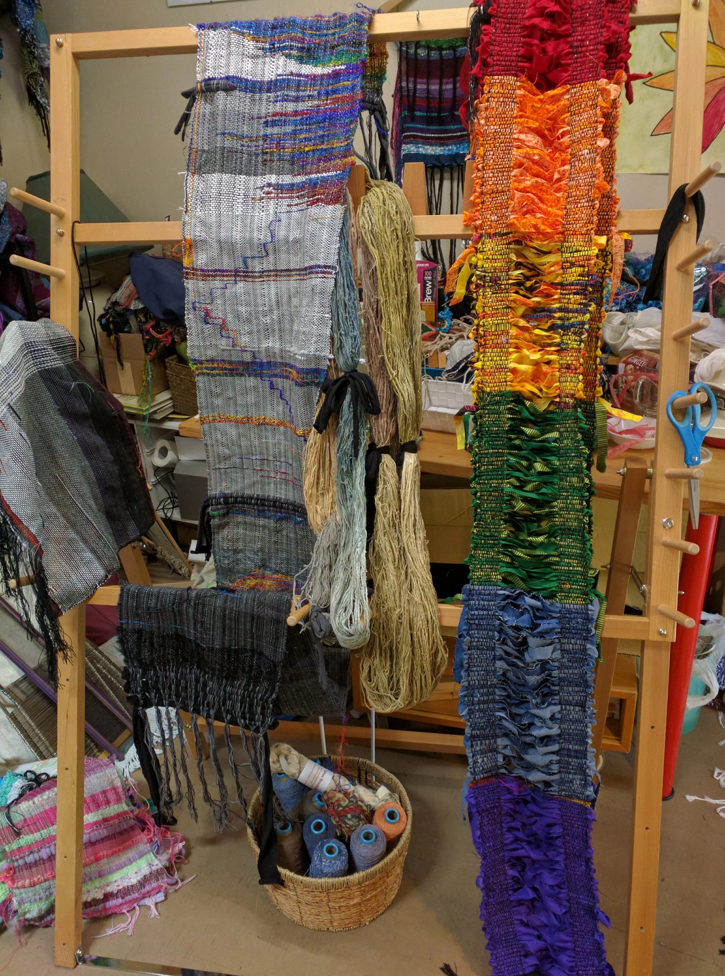 Depression piece (black to white across shades of grey interspersed with sari-silk thread yarn) and Pride-rainbow cool cross, draped over the warping board at Saori Salt Spring , June 2017
