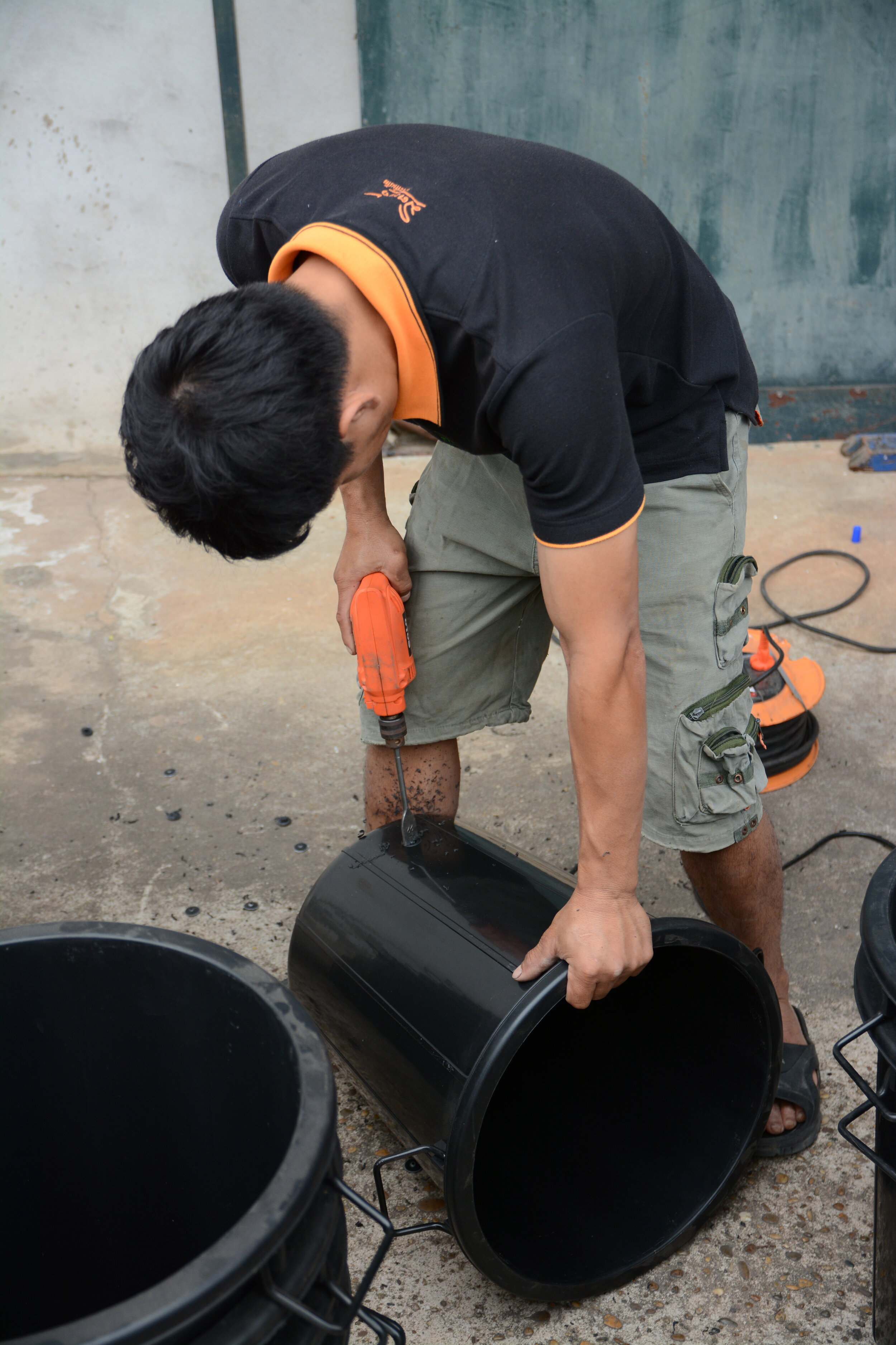   Kamkheo drilling holes and putting the tap on the blue buckets  