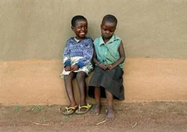 Reggie Achieng, 5, and maurine atiyo, 6, cousins and best friends, sit outside of Atiyo’s mud home. Achieng is known in the village for her contagious smile, a reminder of her uplifting spirit.