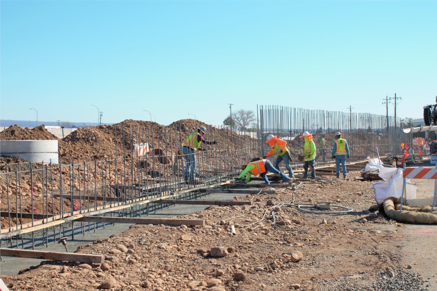 five men wearing neon shirts working on a large cement project.v2.jpg