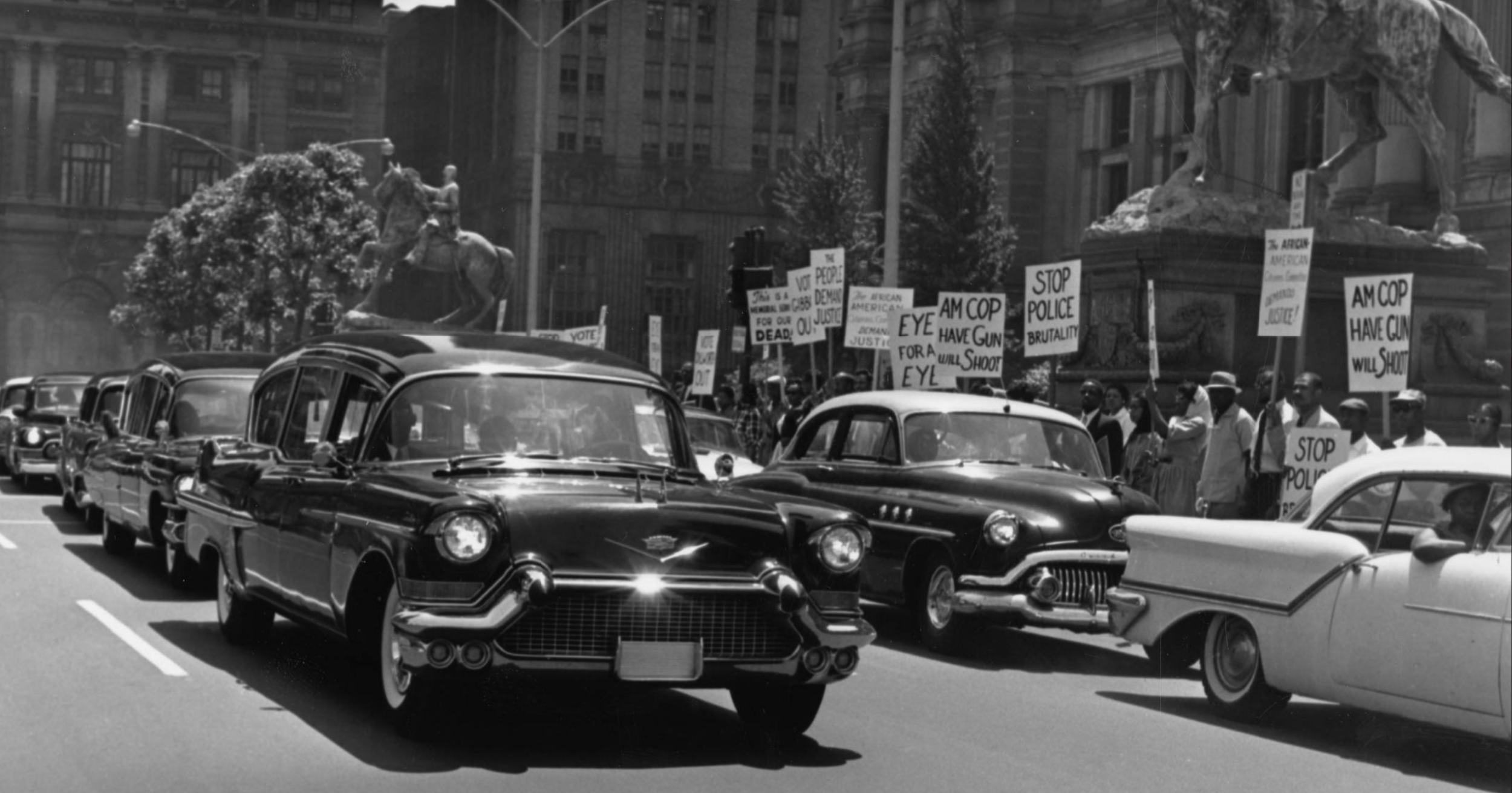   A protest against police brutality, 1960. Hearses carrying the bodies of Ella Lucy Jones and Louise Jones circle Philadelphia City Hall while protestors circle City Hall on foot, carrying signs that read “This is a memorial for our dead,” “The peop