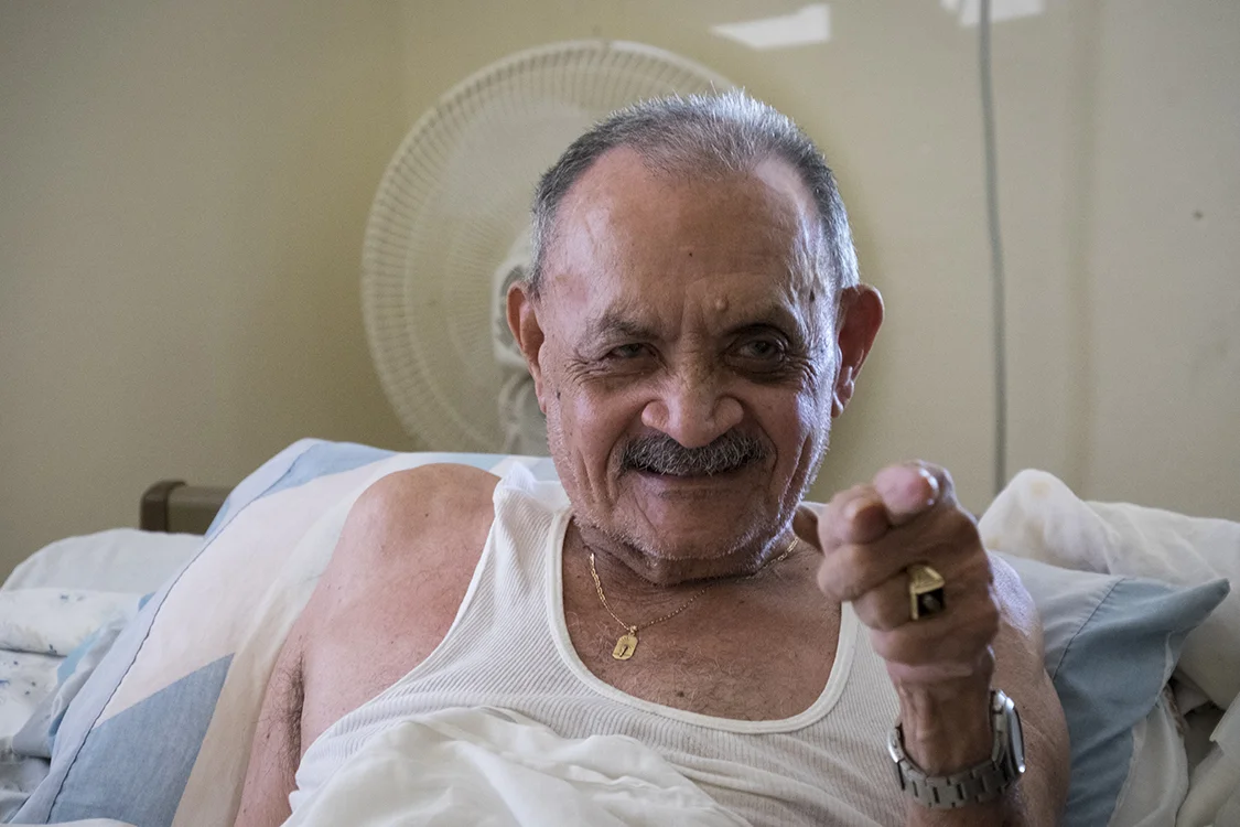 A bedridden man very happy for some friendly faces.