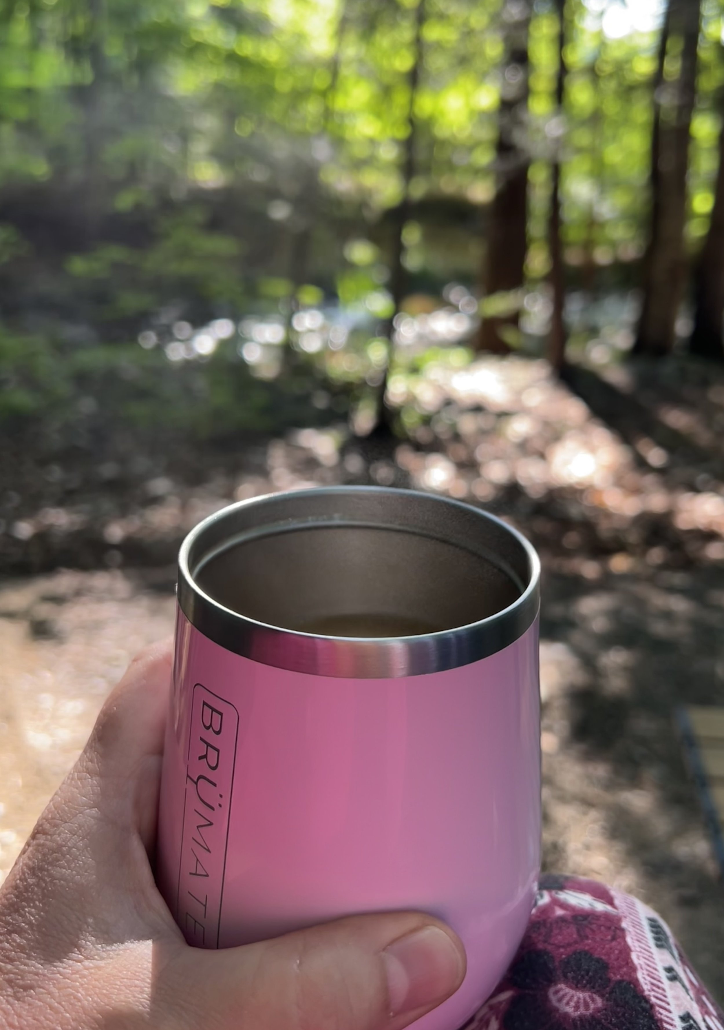 Woman holding a pink coffee mug while overlooking a peaceful river surrounded by trees as a reflection on mindfulness and awareness.
