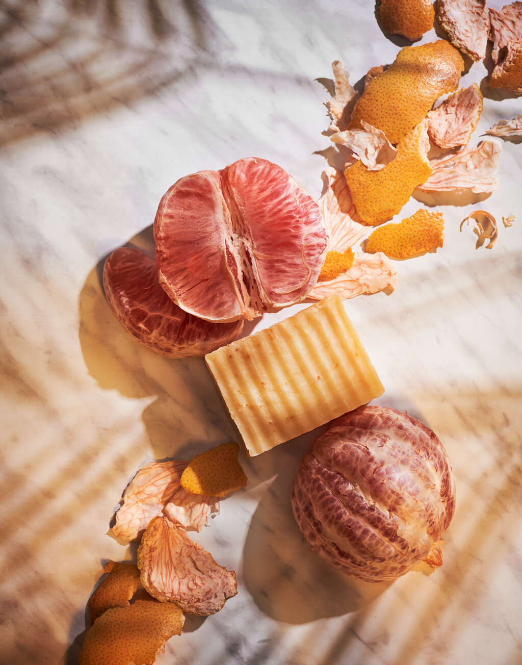  Flatlay of a open grapefruit, grapefruit skin and soap on a marble background. 