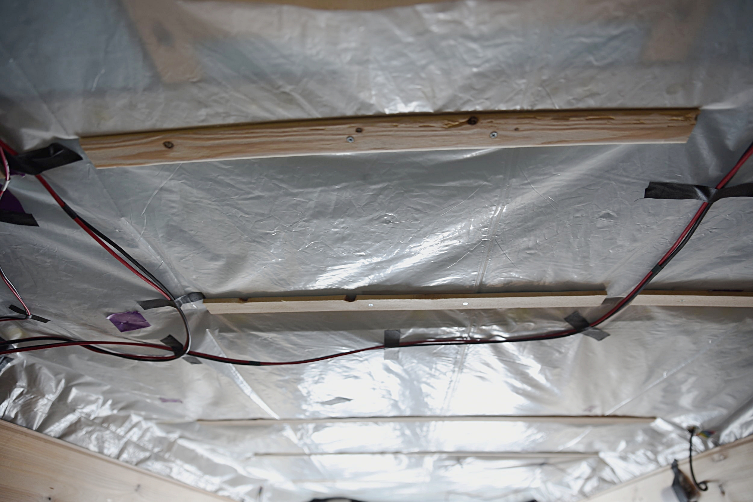 We used lath as a spacer to allow the wires to run underneath the ceiling paneling without being pinched at all. Lath is about 17 cents a piece so it's a lot cheaper than using a thin piece of trim.