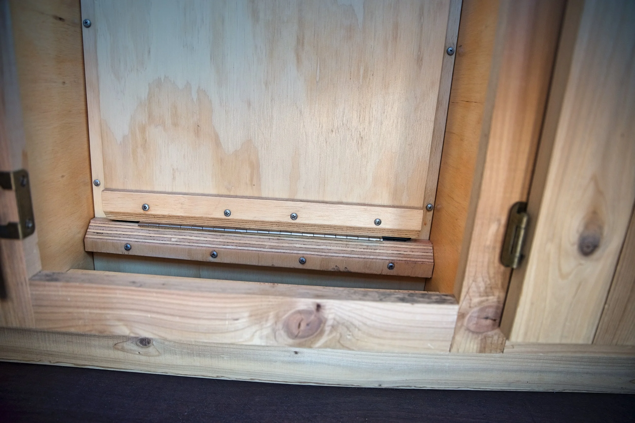We added these two angled pieces of wood around the hinge to reinforce the places where we had accidentally split the plywood a bit when attaching the hinge.