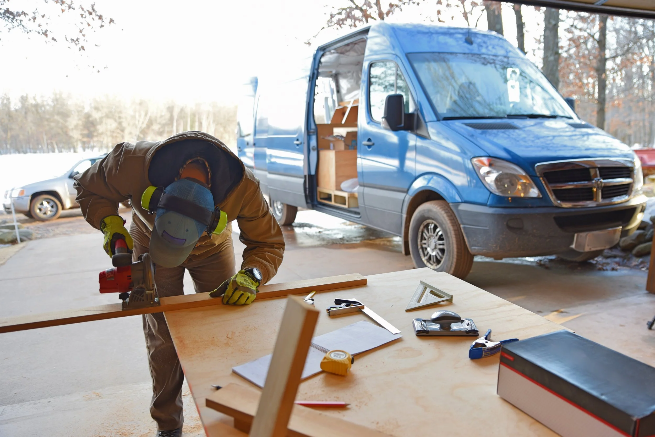 Ian cuts a piece of wood for the cedar plank and brace cabinet doors.