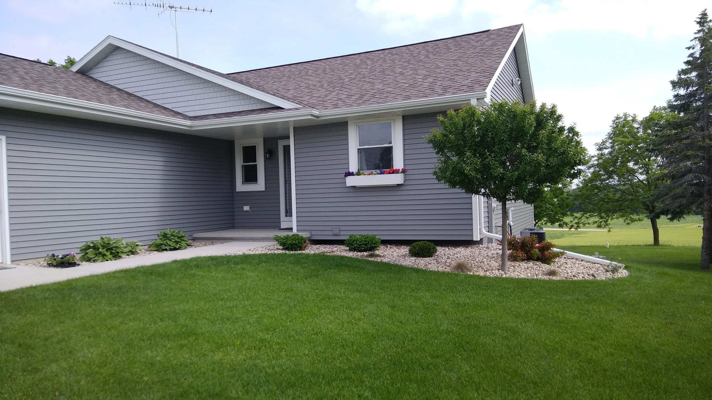 Nicely landscaped grey house with fresh cut grass