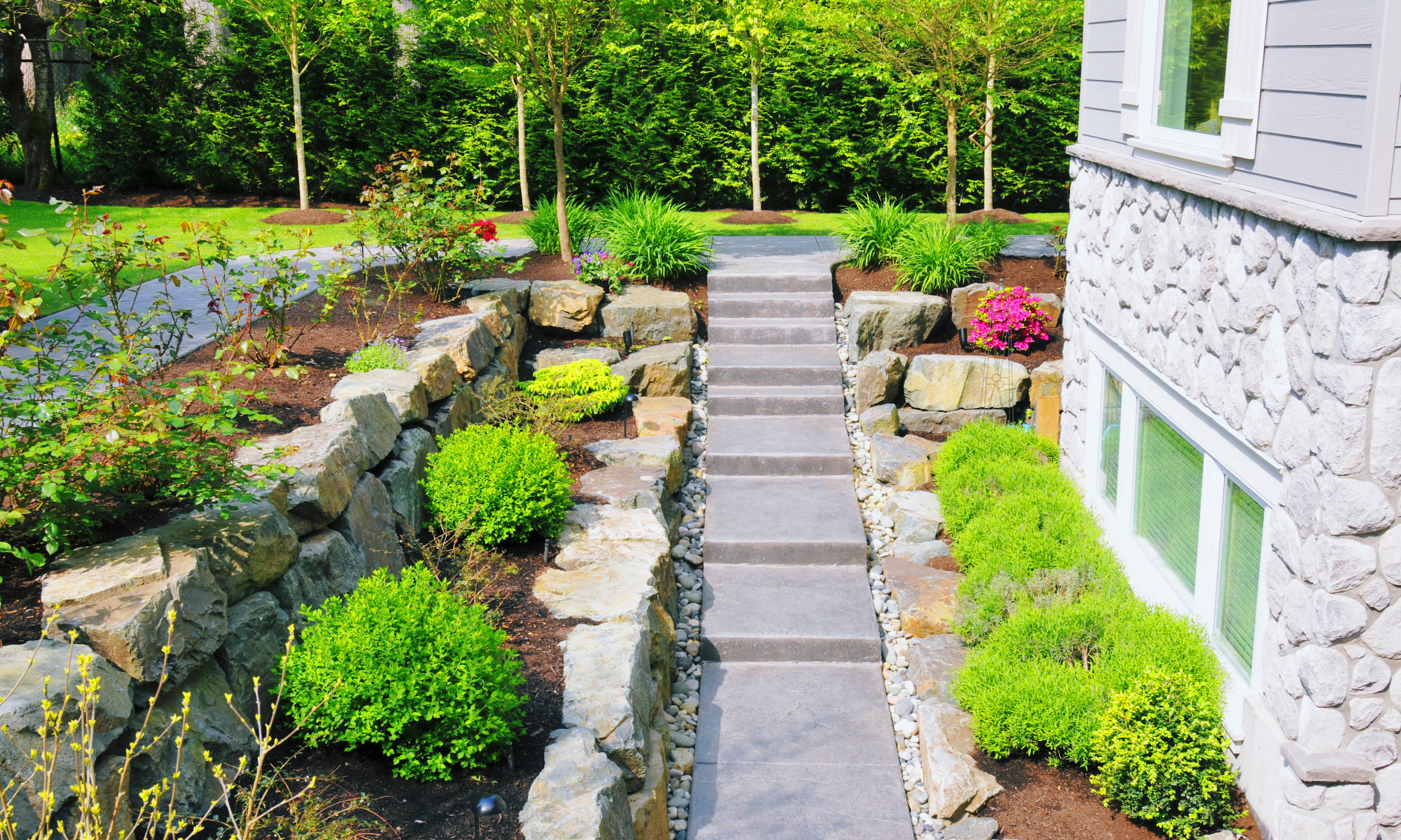 beautiful landscaping with big stones, mulch and shrubs