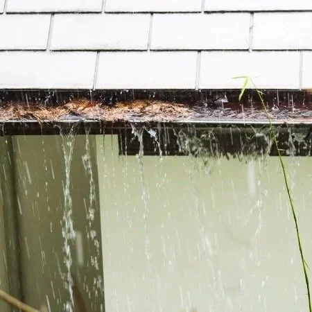 water overflowing from gutter clogged with leaves