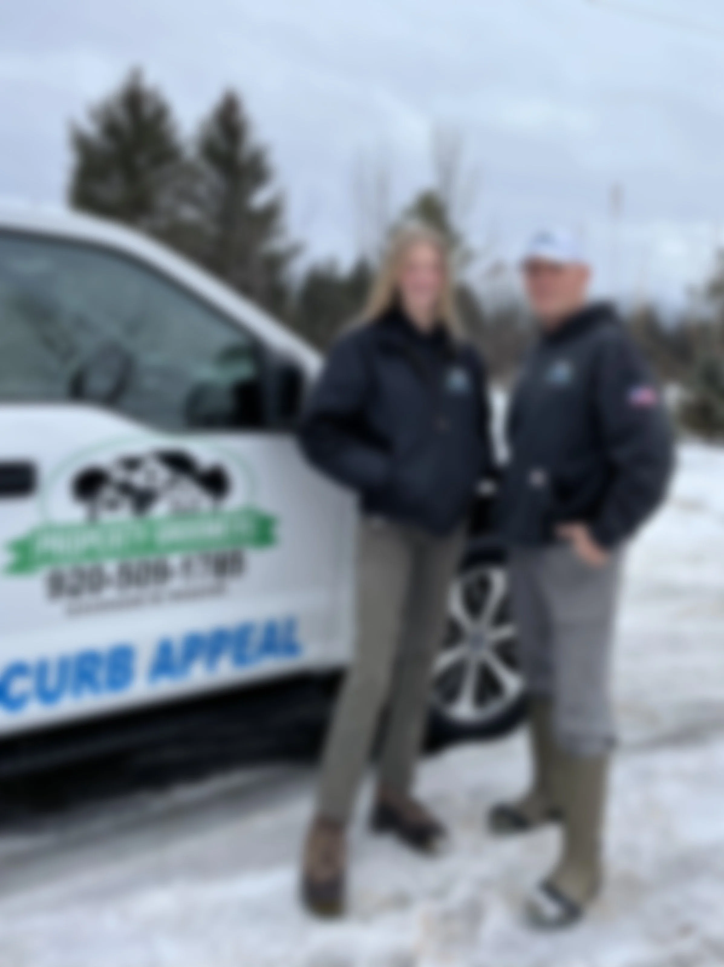 Owners of The Property Groomers smiling standing in front of truck blurred