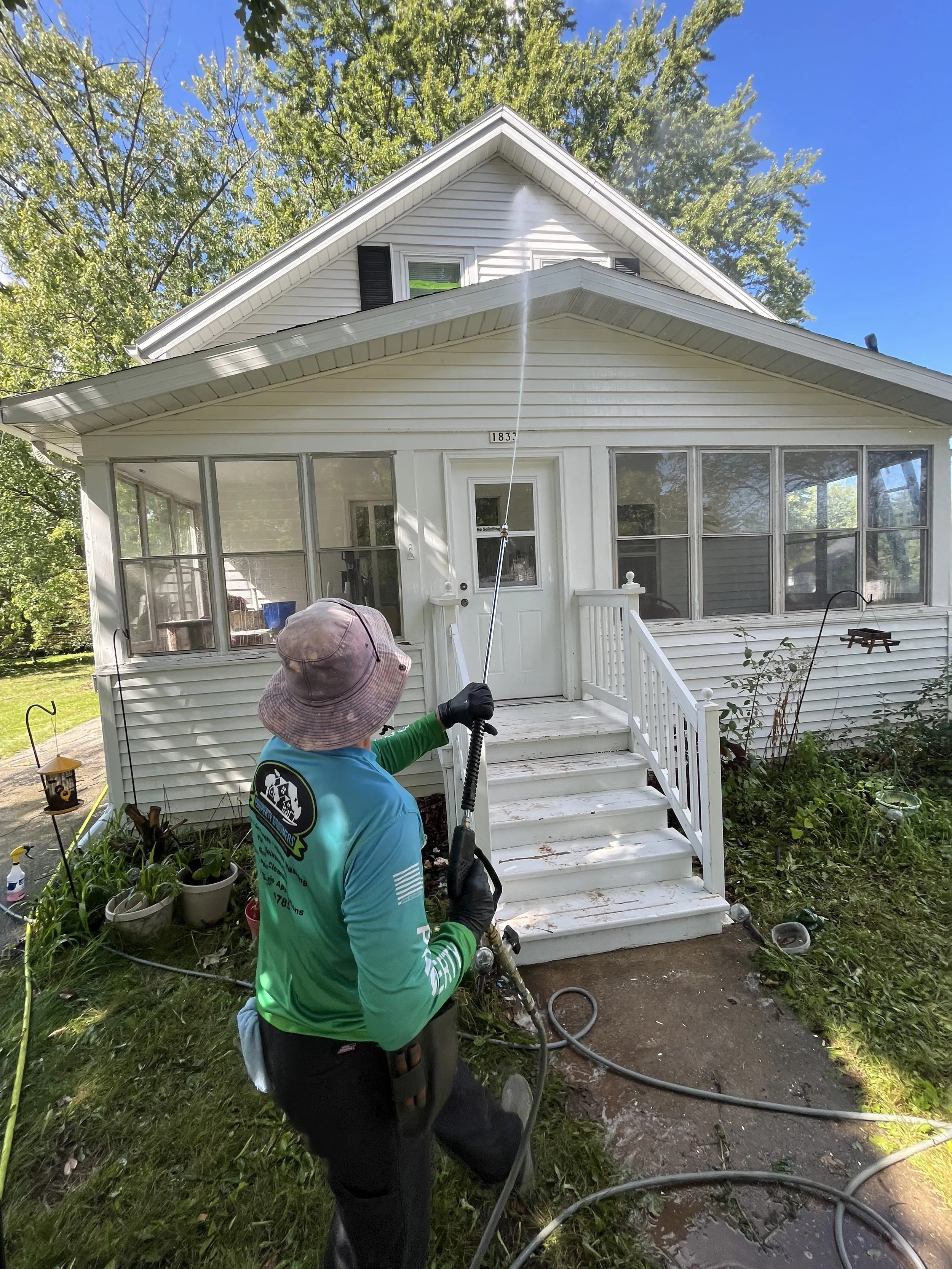 Girl soft washing a house to clean debris off the side