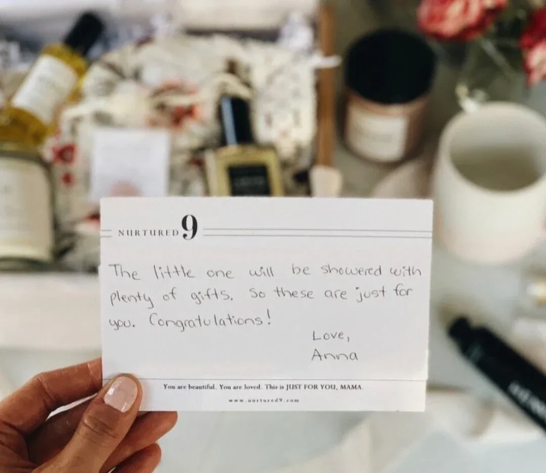 mom holding a handwritten notecard in front of a gift box