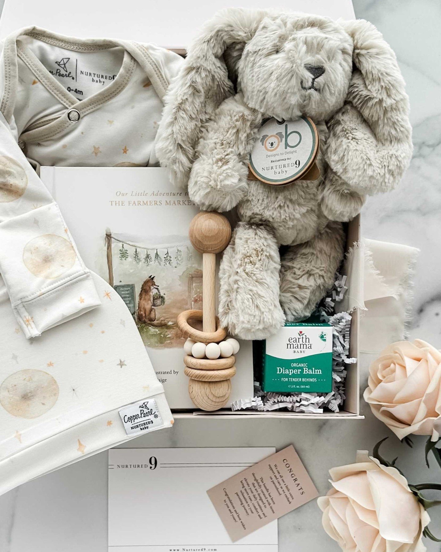 The sweetest Nurtured 9 New Family Gift Box with something for baby to wear, snuggle, read, and play with - plus diaper balm because that always comes in handy!