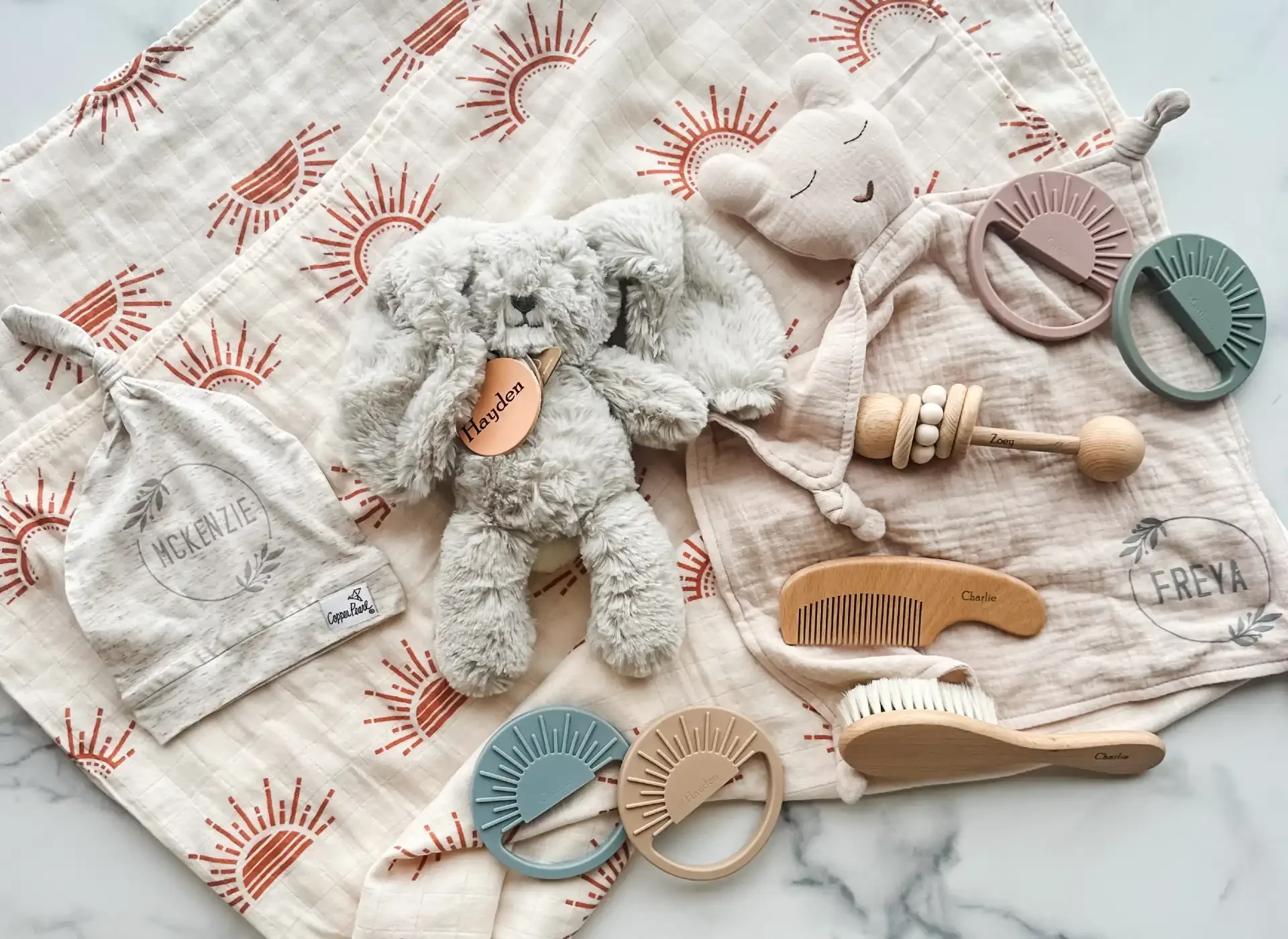 personalized baby gifts including onesie, swaddle, wooden brush set, lovey, rattle and stuffed animal