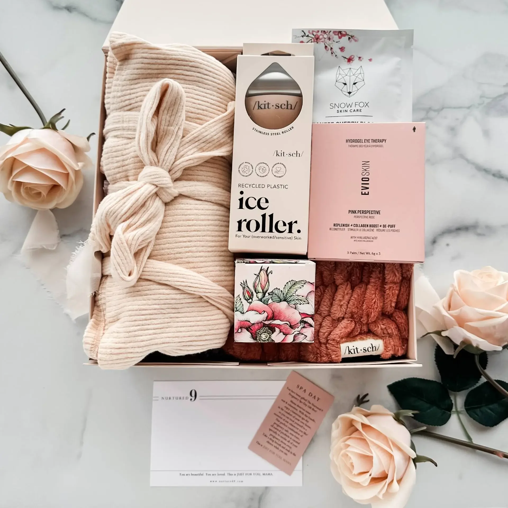 spa themed gift box with maternity robe, ice roller, eye patches, sheet mask, lip scrub, and flowers