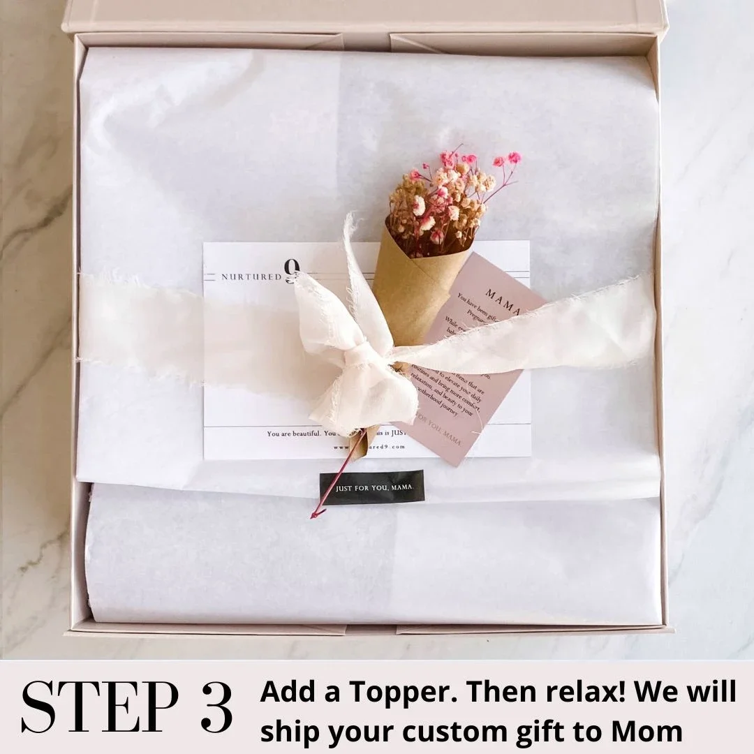 an open pregnancy gift with tissue paper, ribbon, and dried flowers
