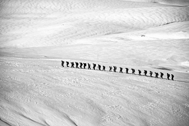 Imagery of a team of explorers walking together on a snow field - they'll get to their destination sometime.