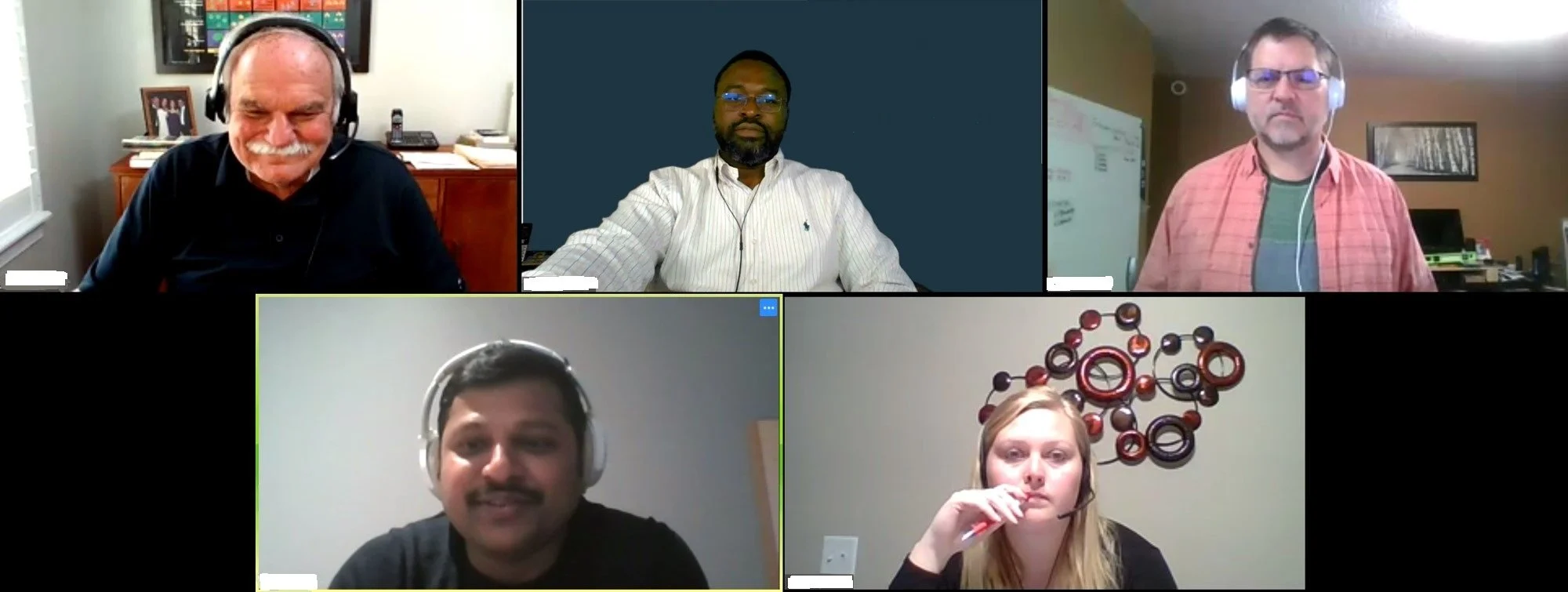 A screenshot of five people in a video conference grid, some wearing headsets.