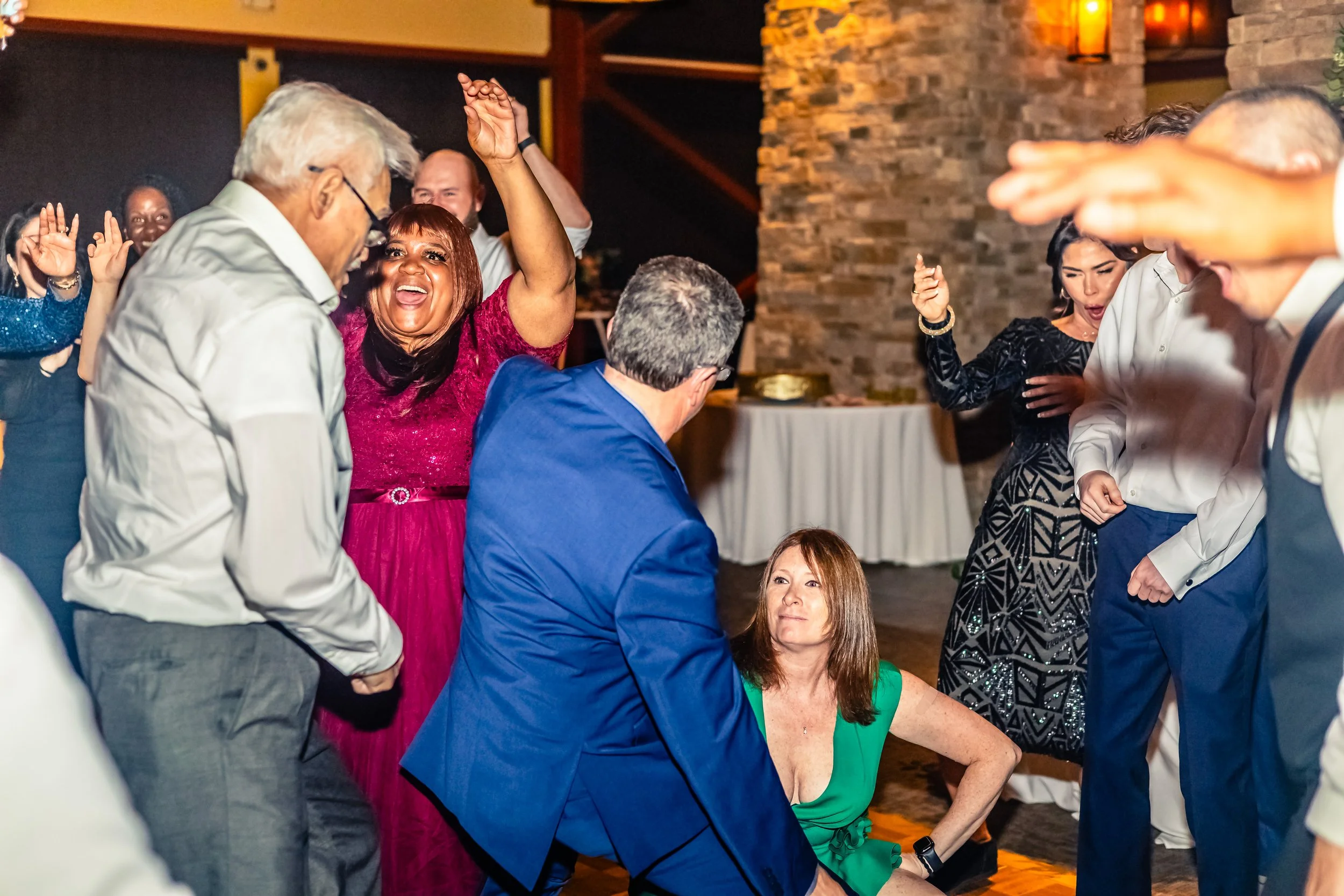 People dancing and enjoying themselves at a party or celebration indoors, with various colorful outfits and expressions of happiness.