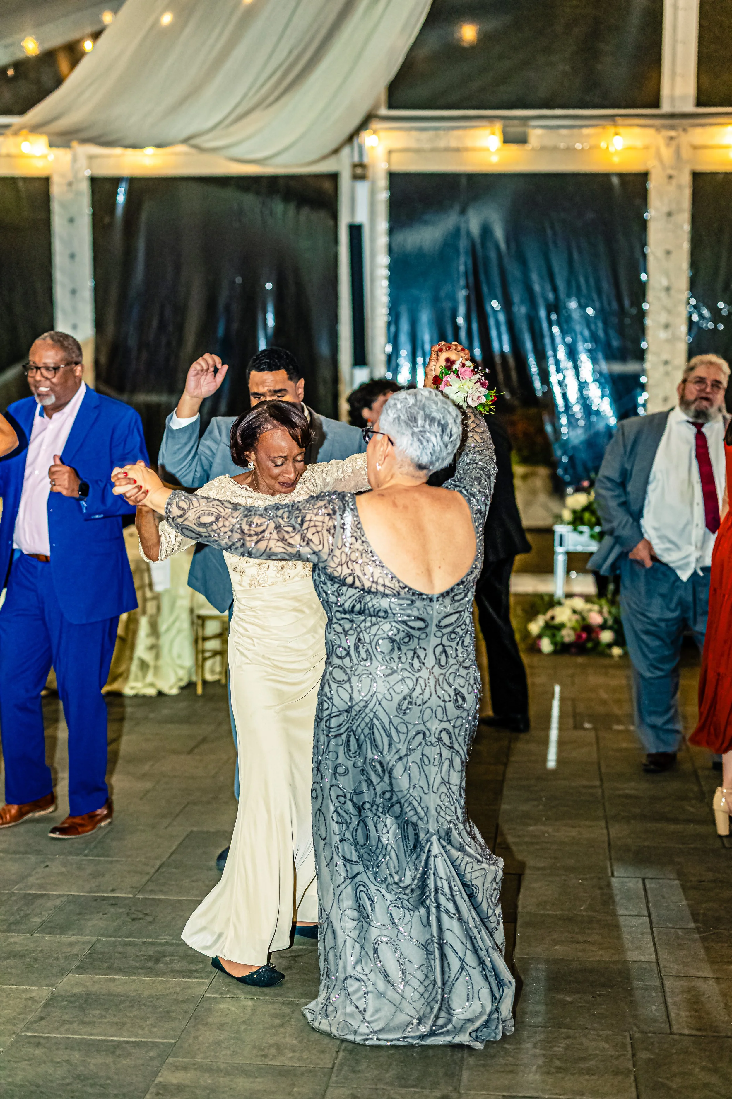 People dancing at a wedding reception inside a decorated venue at night.