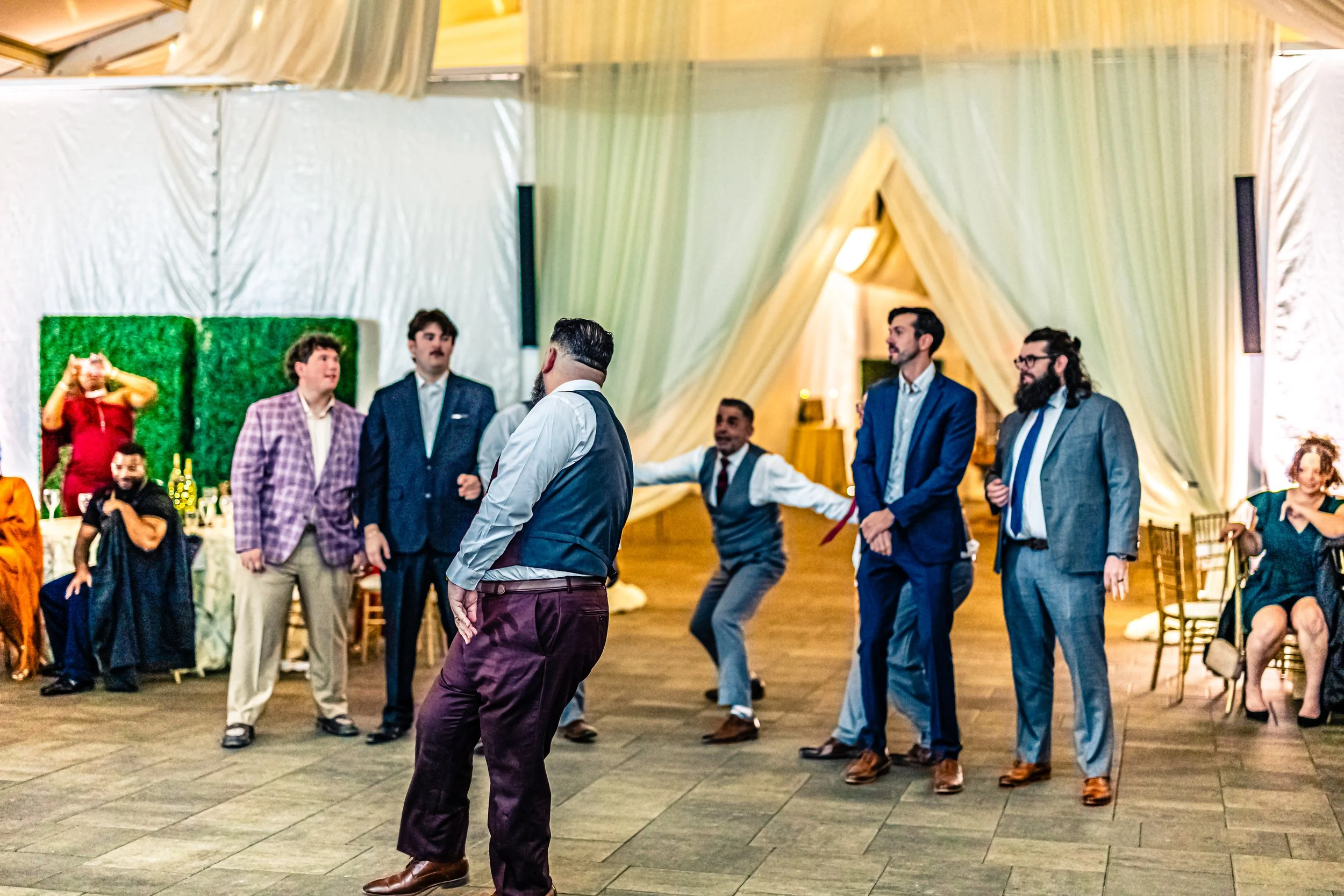 People dancing at a party or wedding reception with elegant decor and guests sitting at tables.