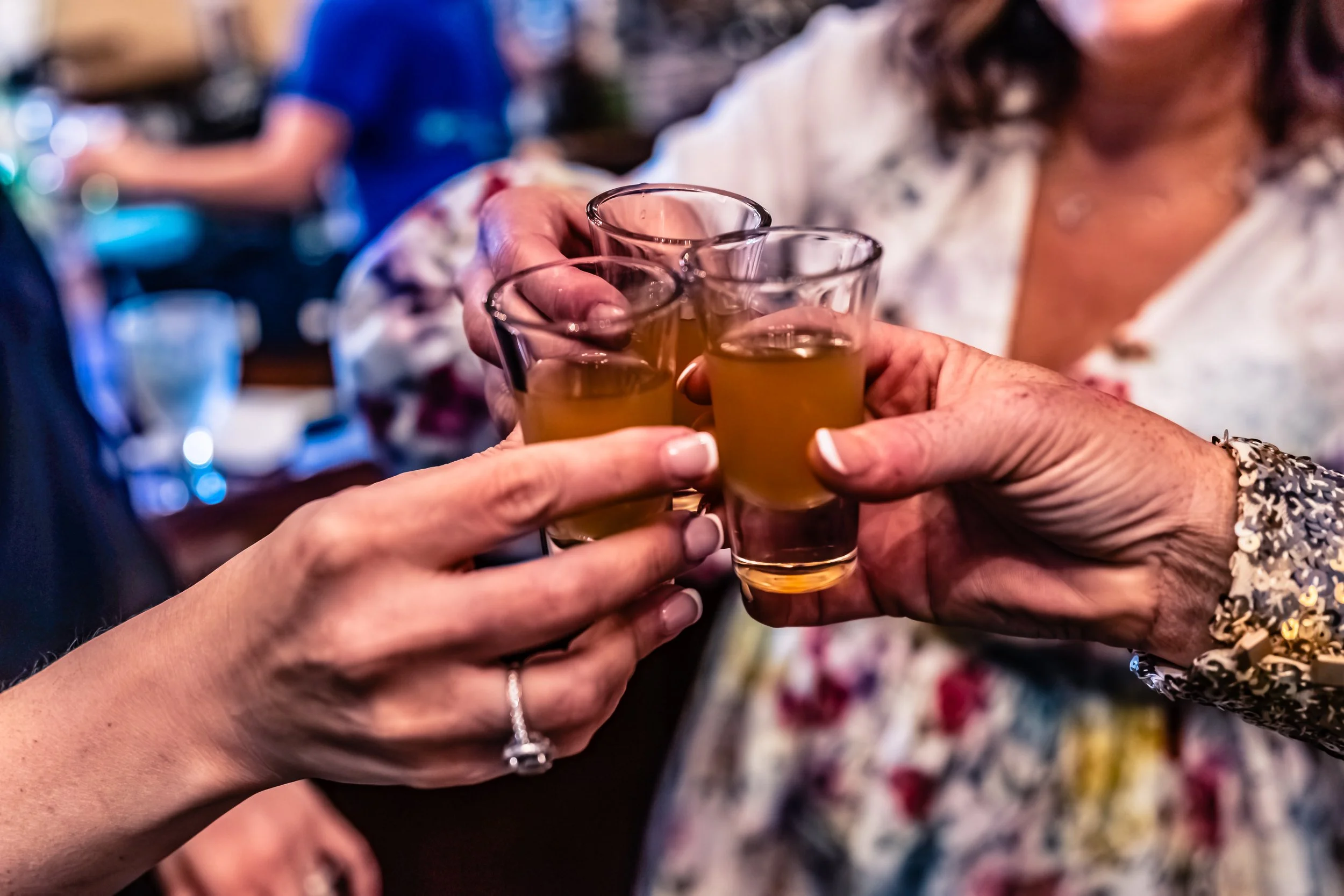 People clinking shot glasses filled with a yellow drink in a celebration