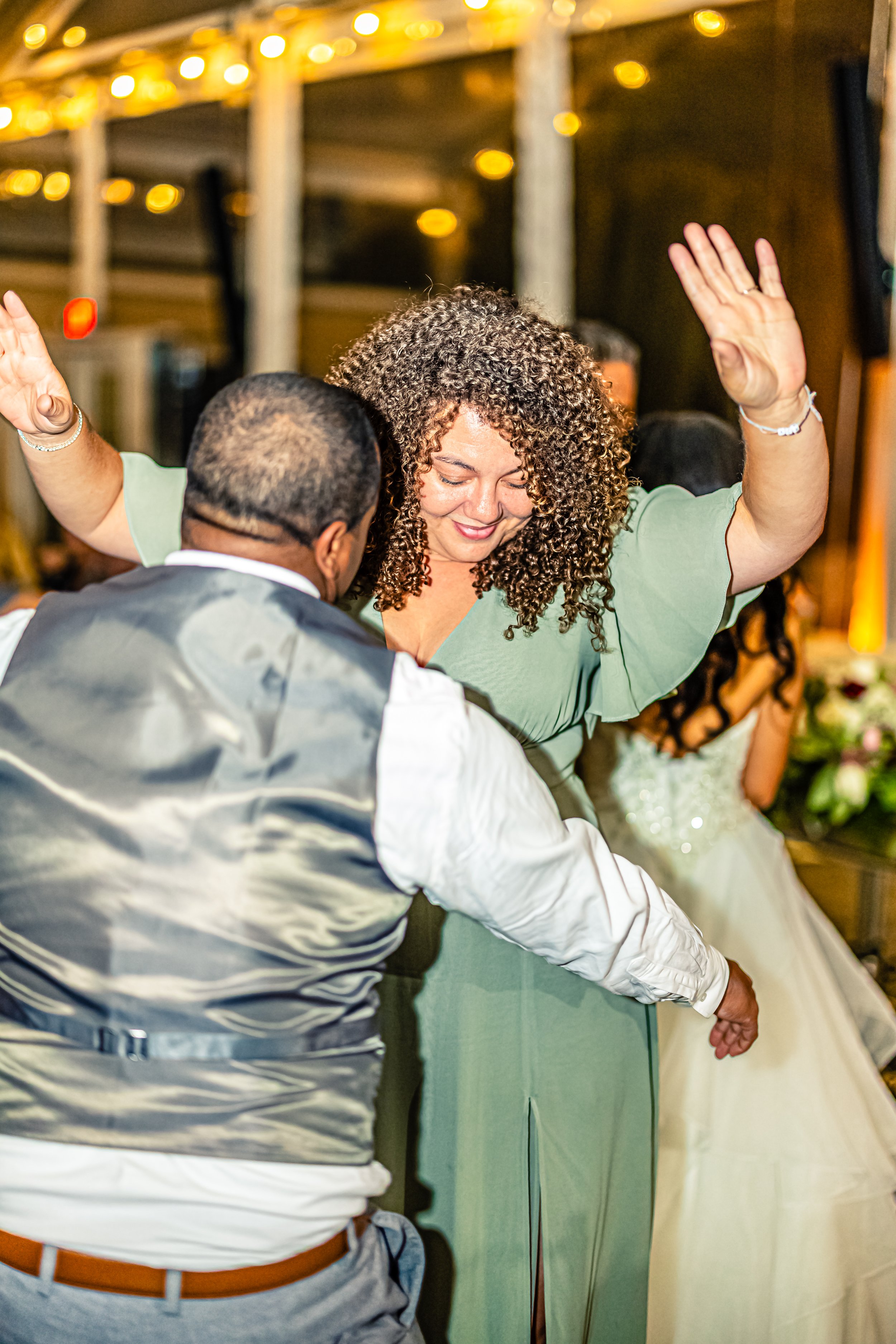A woman in a green dress dancing with a man in a vest at a celebration event.