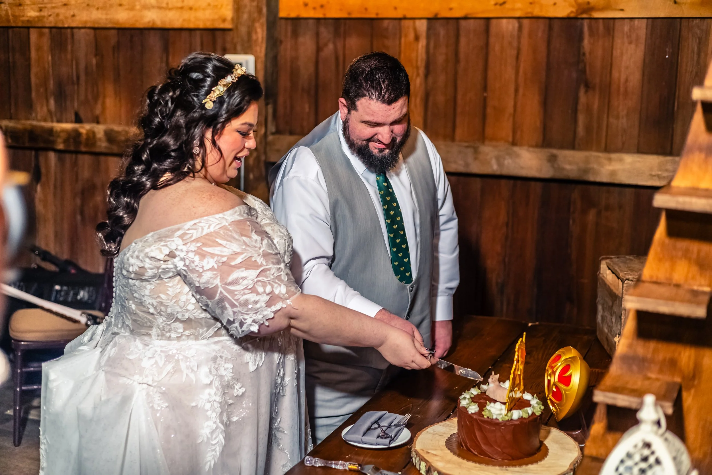 A bride and groom sharing a moment cutting a wedding cake in a rustic wooden room.