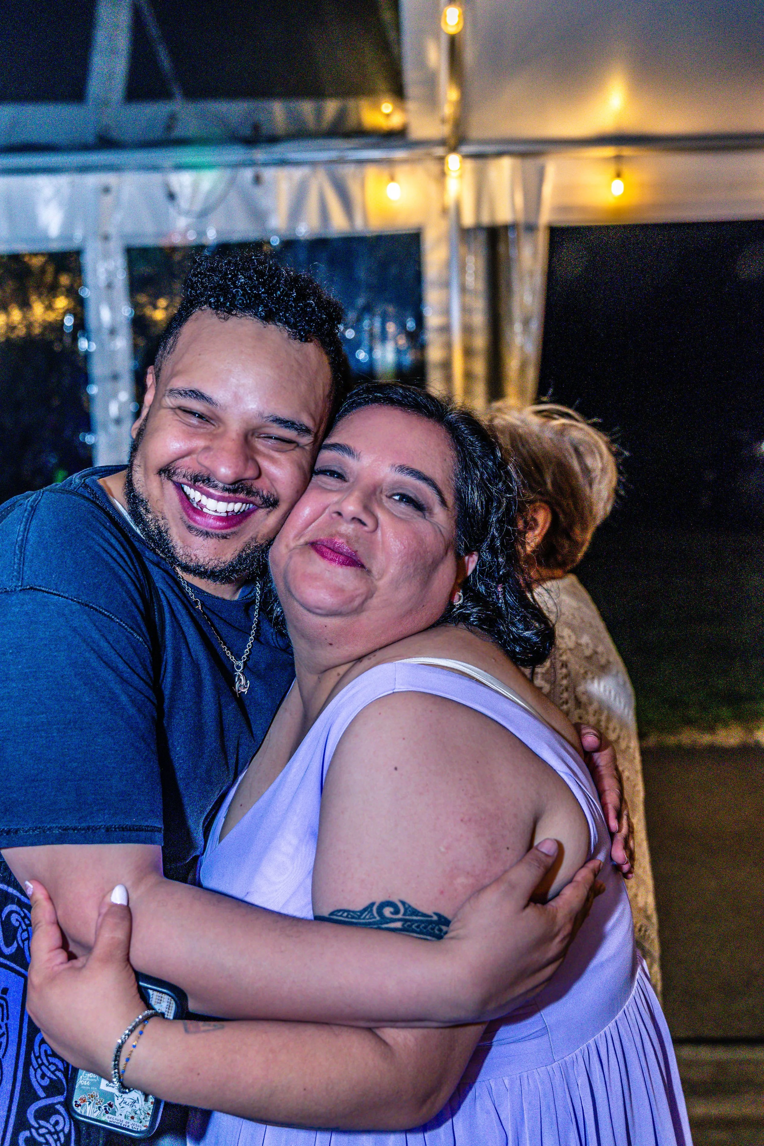 Two people hugging and smiling at a nighttime outdoor gathering or party.