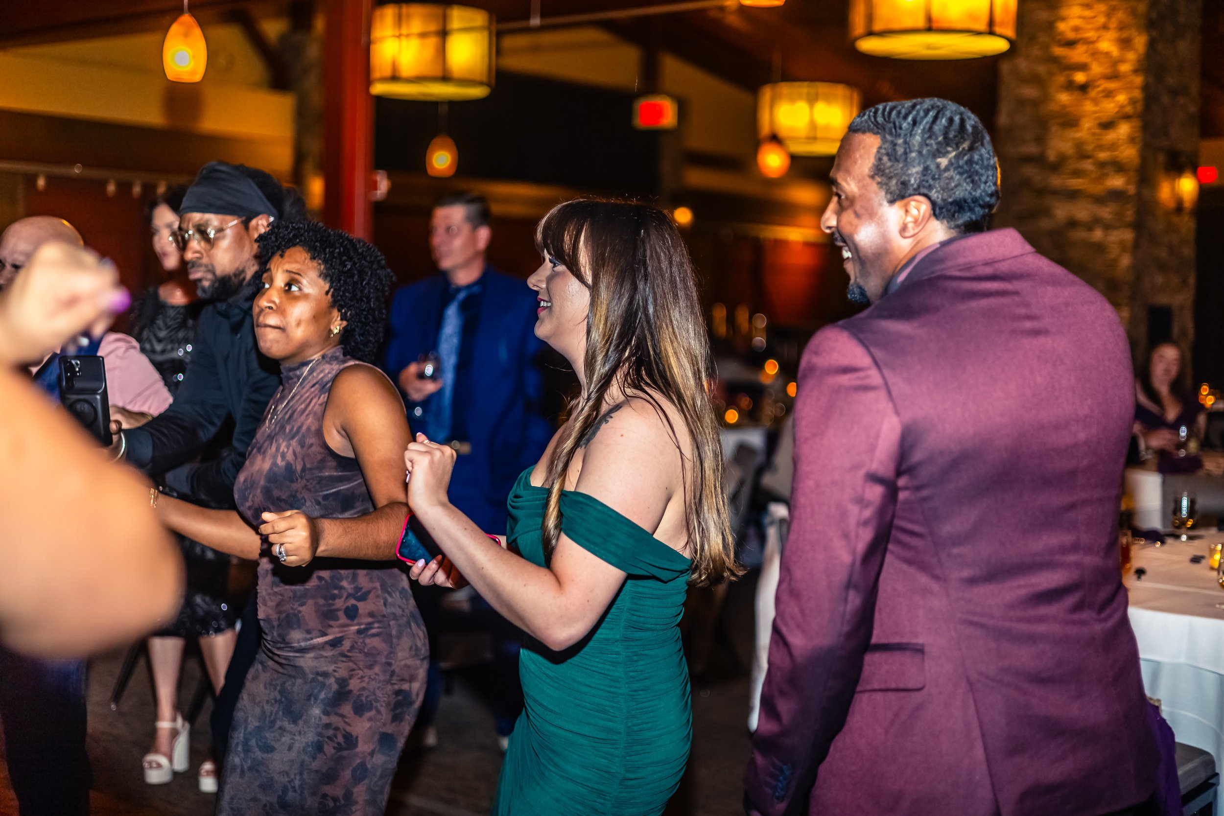 People dancing and mingling at a lively social event in a warmly lit venue.