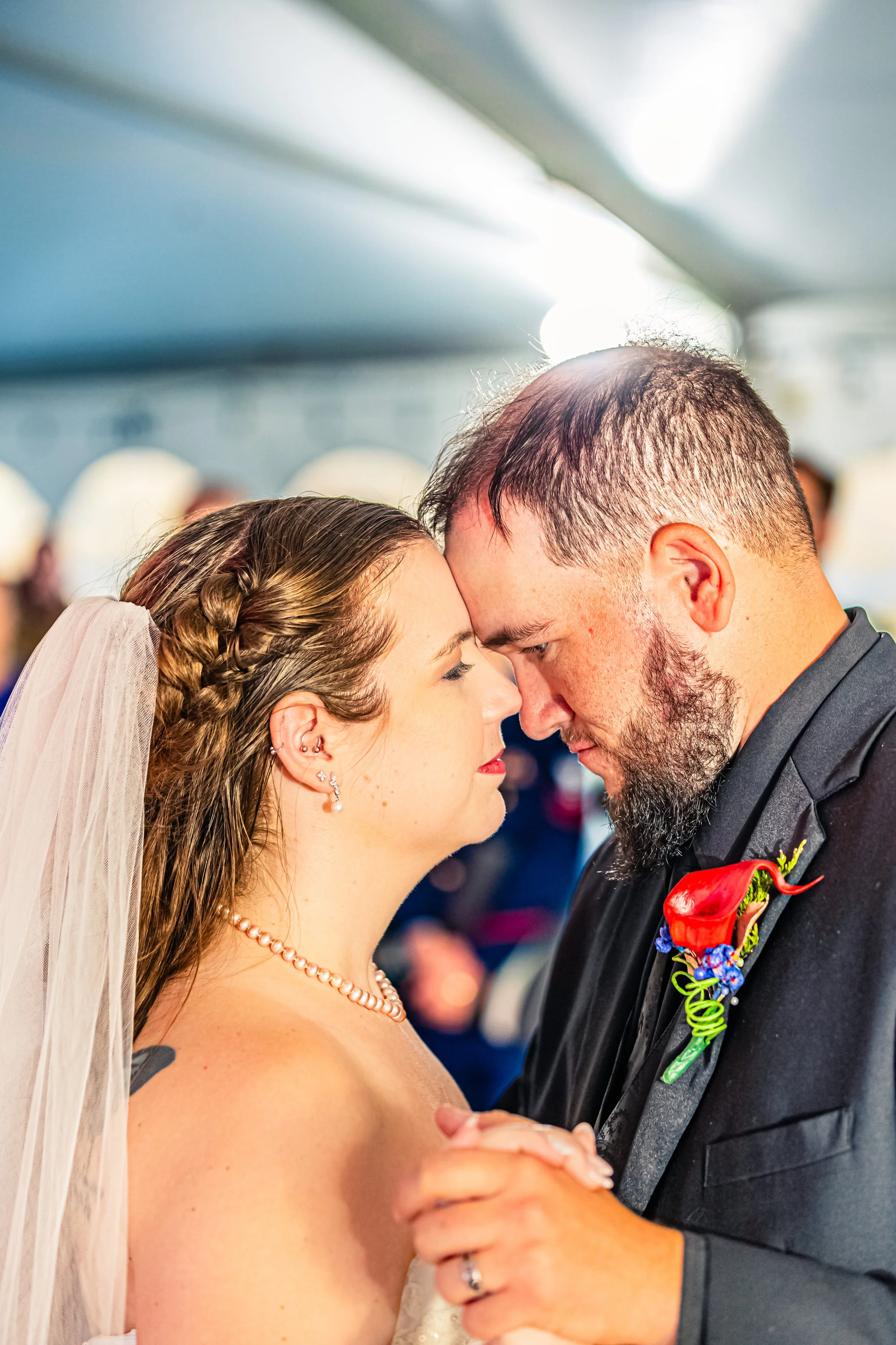 A bride and groom sharing a close dance at their wedding, with foreheads touching and eyes closed.