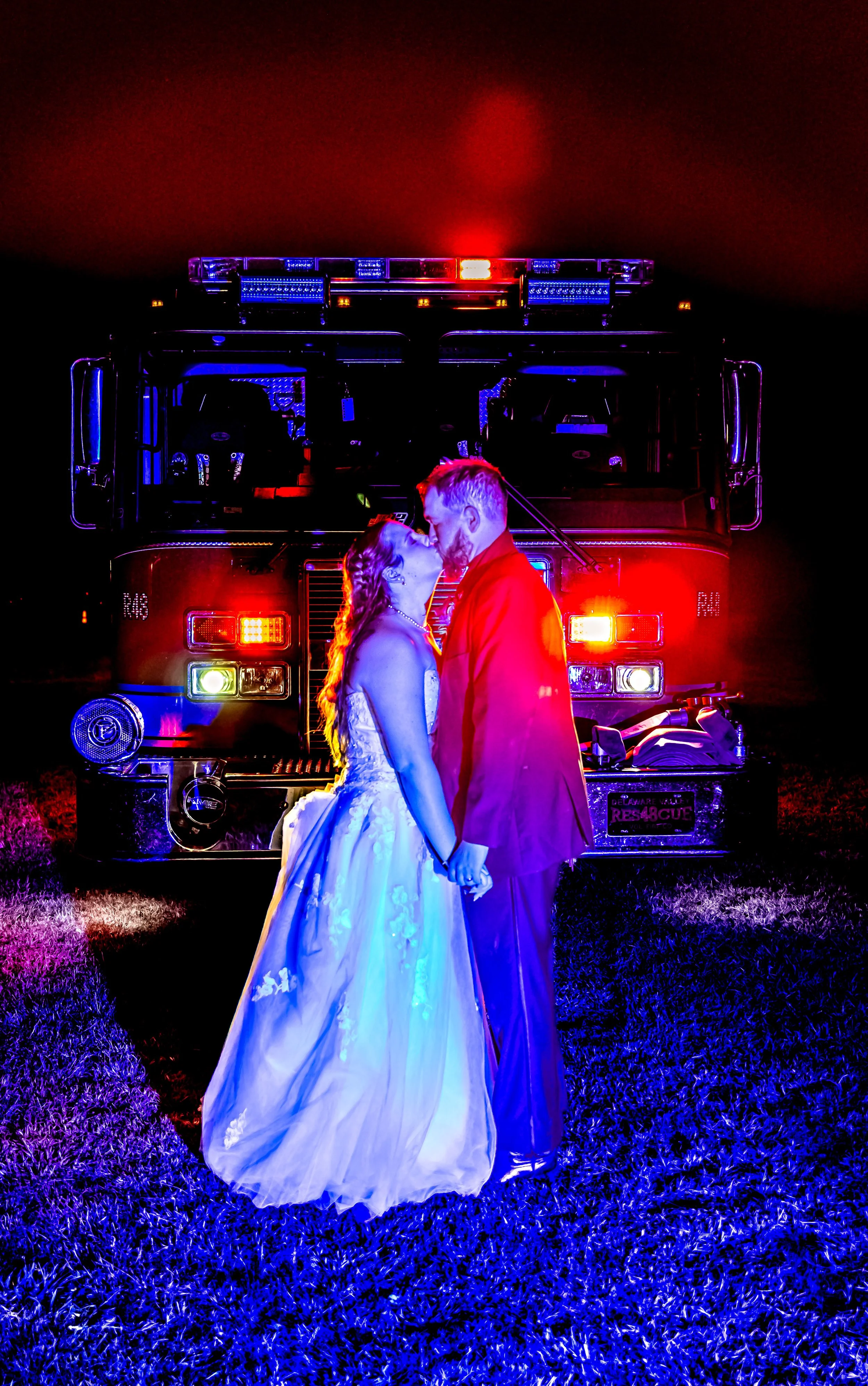 night shot couple kissing in-front of a fire. truck with the lights on