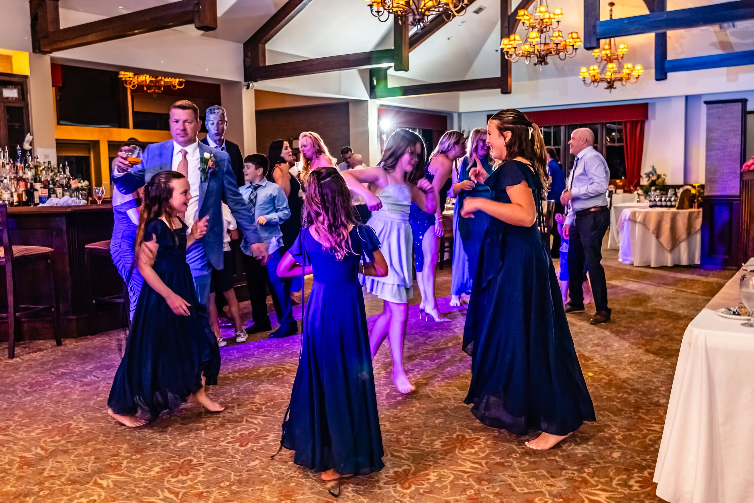 People dancing and socializing at a wedding reception in a decorated banquet hall.