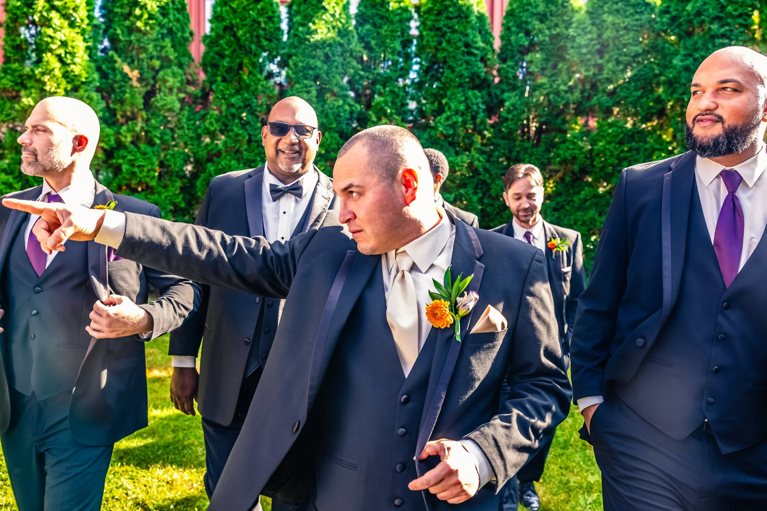 Group of men dressed in suits outdoors, with one man pointing