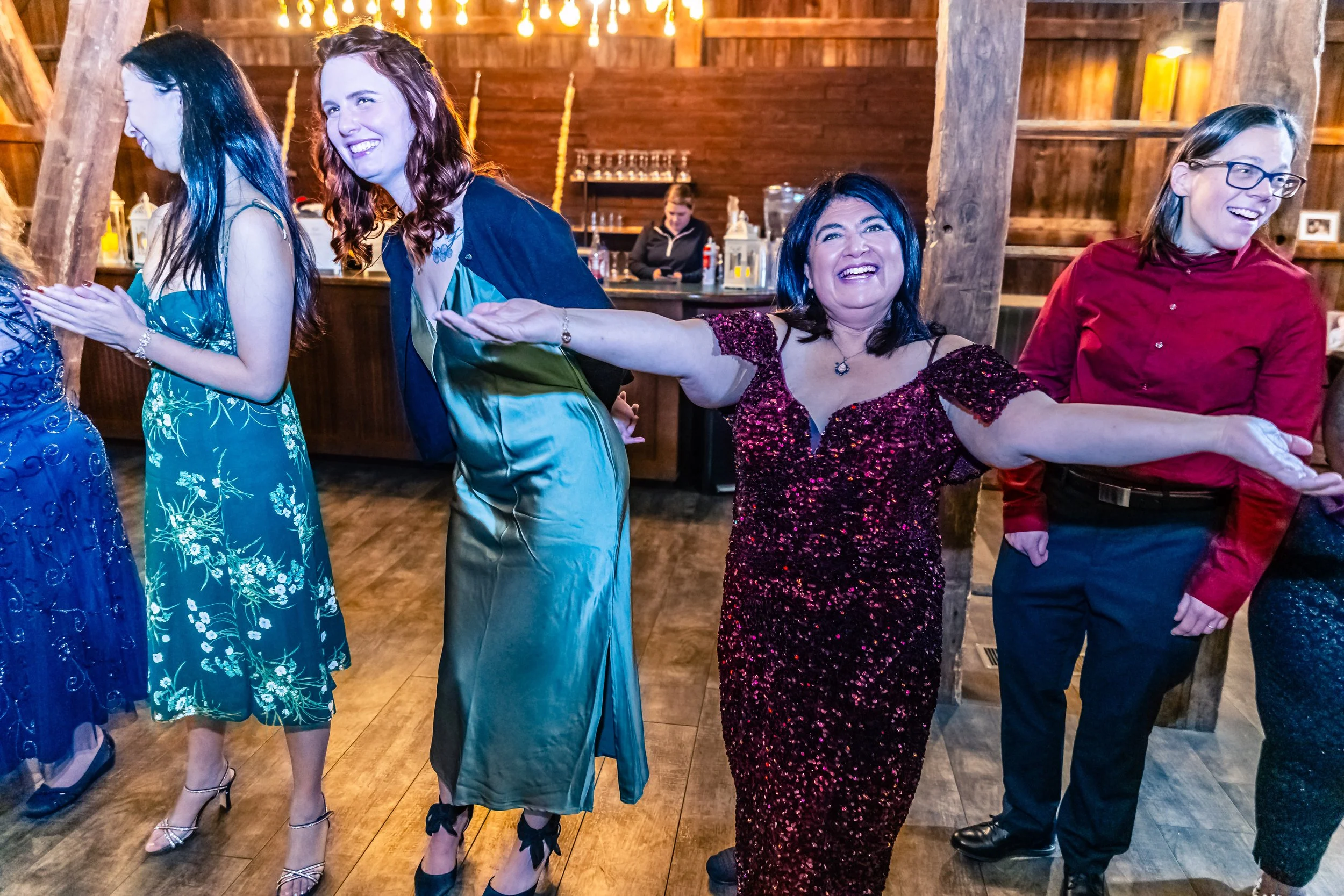 People dressed in formal attire enjoying a dance or celebration in a rustic wooden venue.