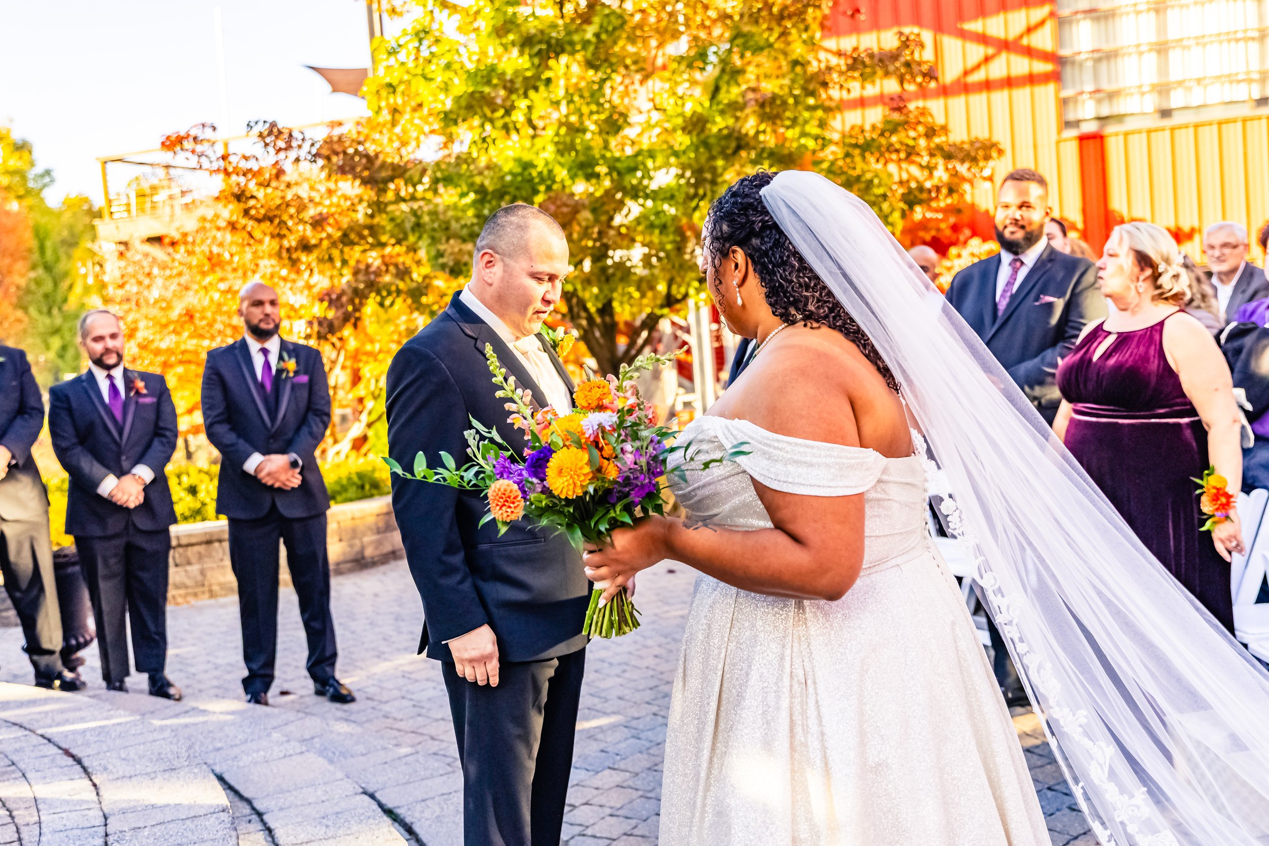 Bride and groom exchanging vows during outdoor wedding ceremony with guests watching.