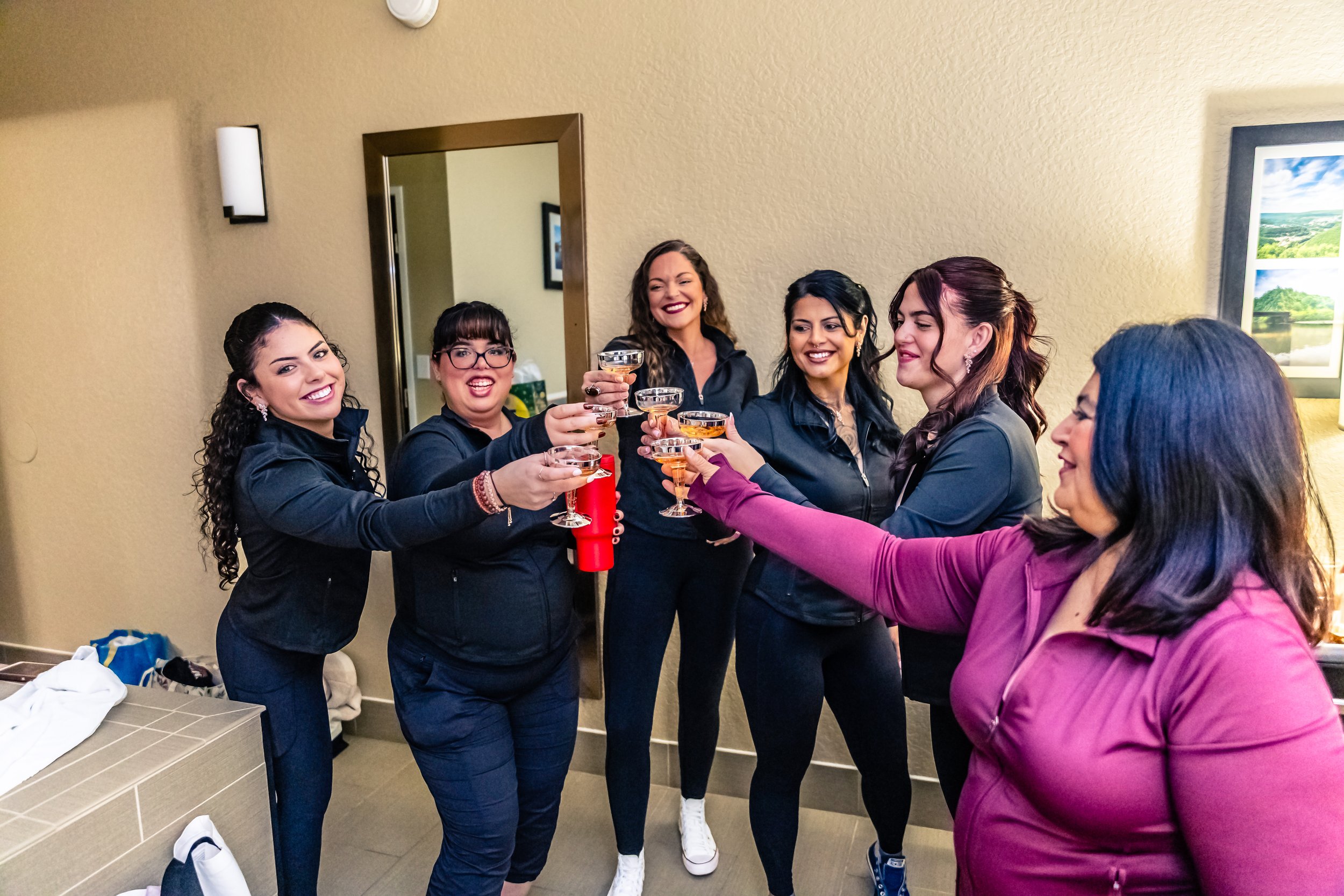 Group of women celebrating with drinks in a room, smiling and toasting.