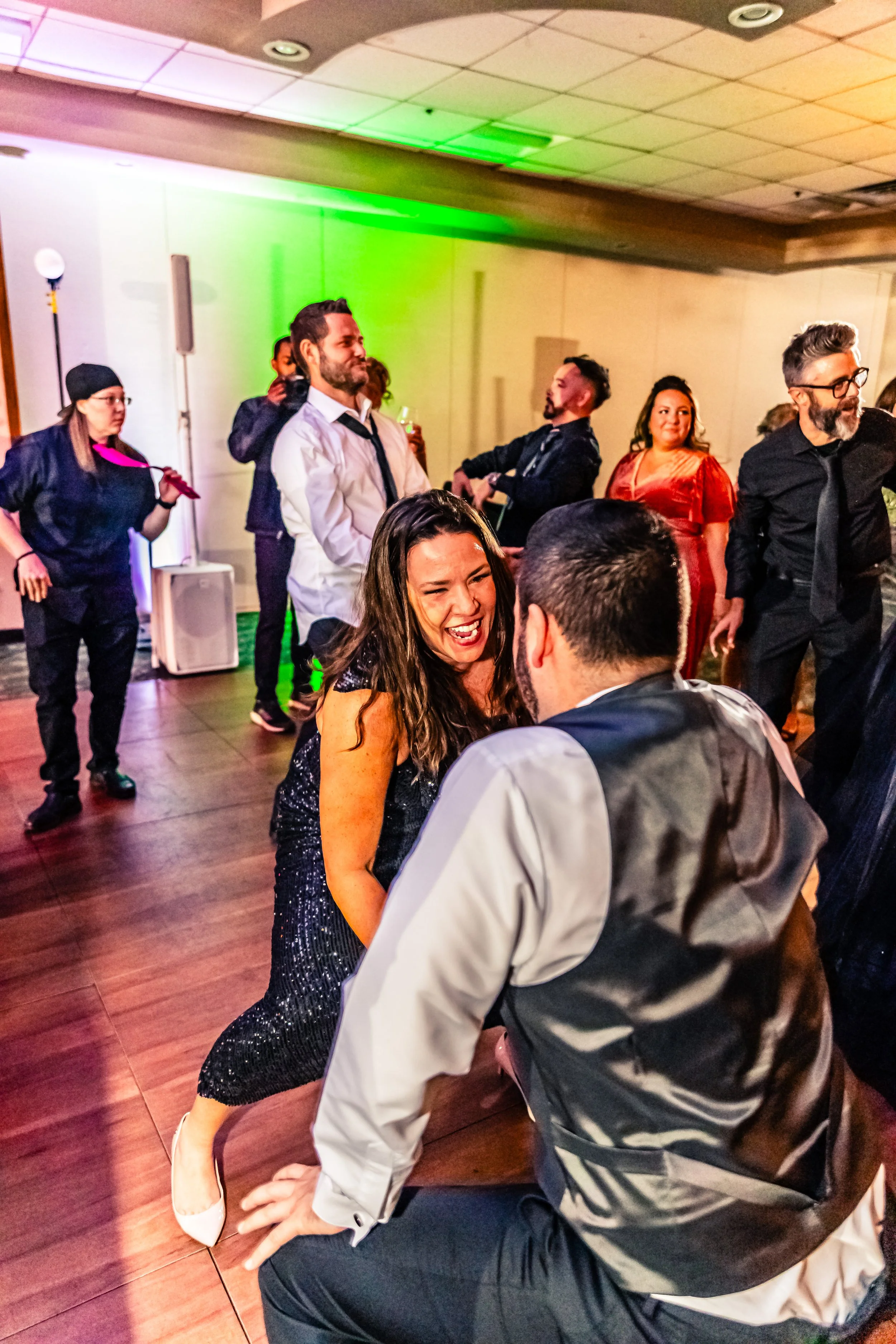 People dancing and socializing at a lively indoor party with colorful lighting.