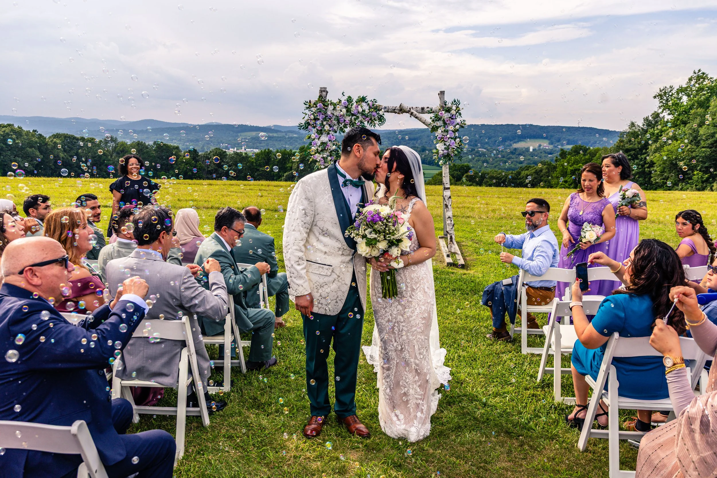 young couple kissing after wedding vows, walking in the aisle, wedding guests blowing bubbles in the background, Born to Run, Pennsylvania