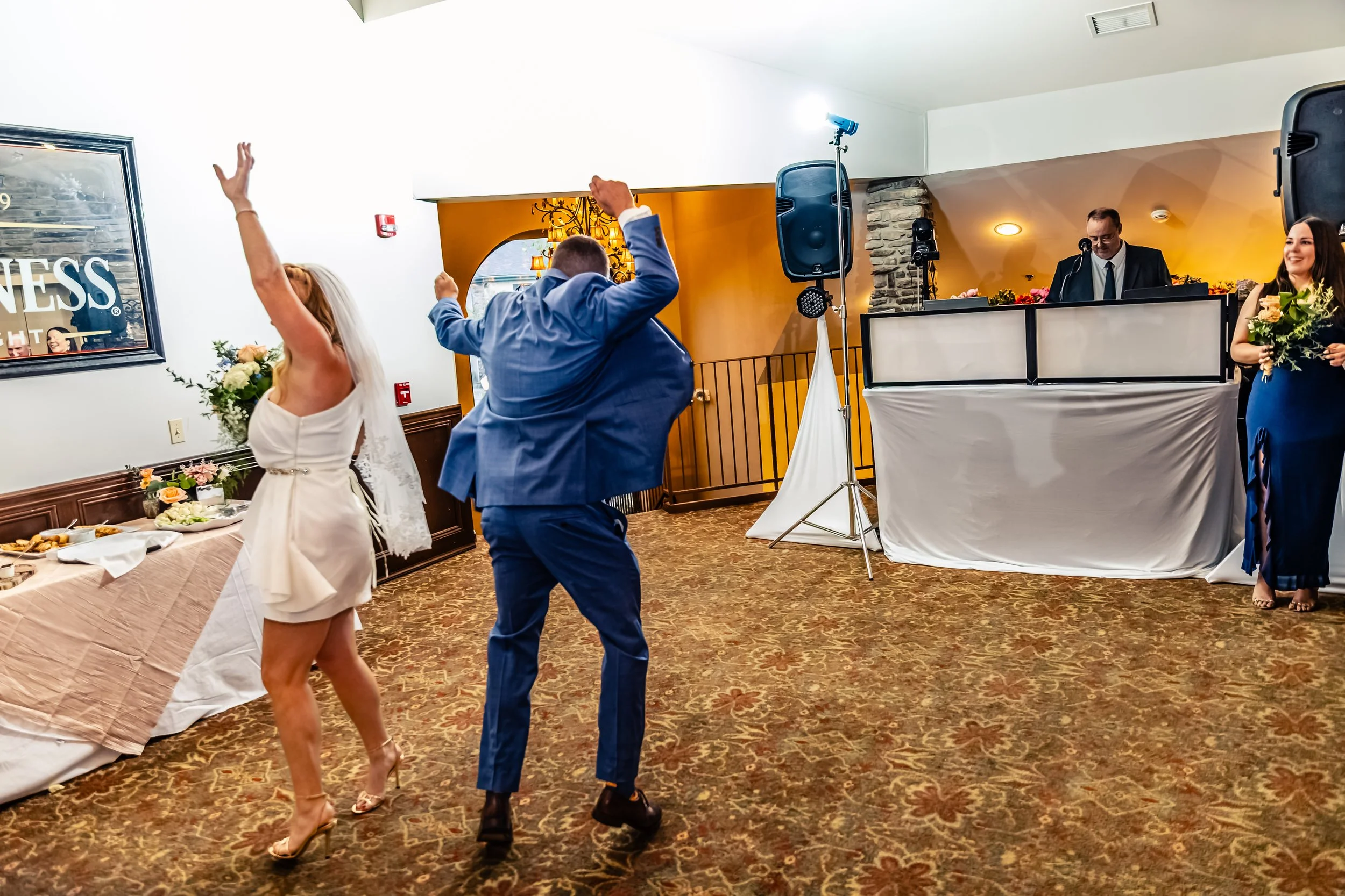 Bride and groom dancing at wedding reception with DJ and bridesmaid in background