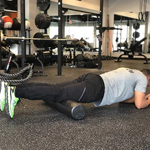 To begin foam rolling the quads, place the top of the knees on the foam roller while assuming a plank position. Start with both legs on the roller to gauge how much pressure you prefer.