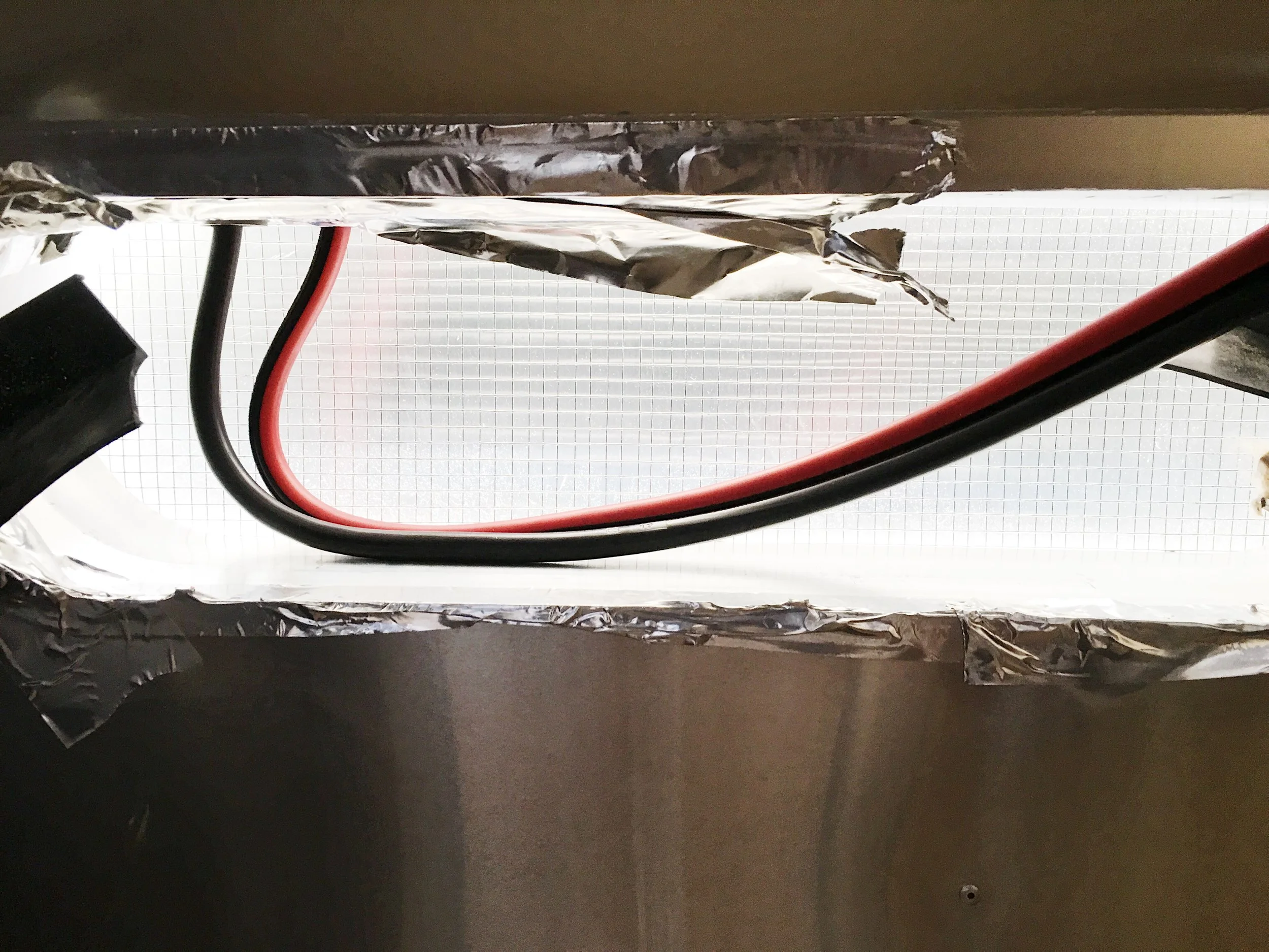 View from the refrigerator looking up at the vent. The end at the top of the image is exiting the vehicle through the vent. The part on the right is what we have to route inside the trailer.