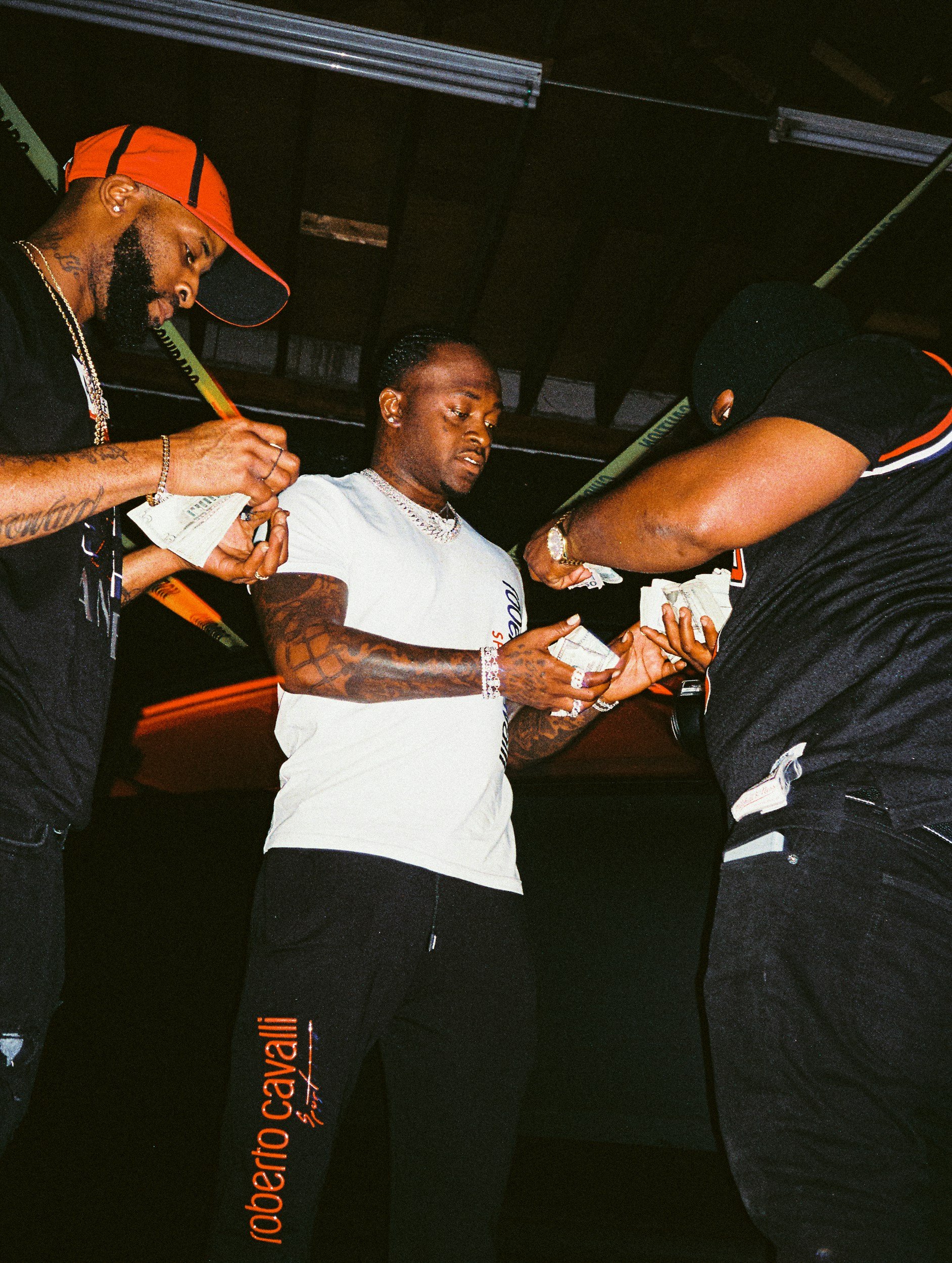 Three men exchanging money in a dark room, with one of them handing bills to the others.