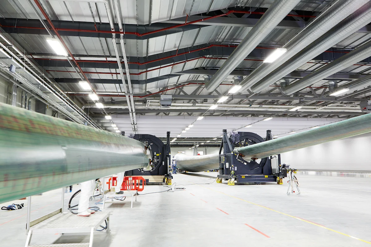 Large industrial wind tunnel with two massive sections connected by a long, cylindrical, greenish pipe.