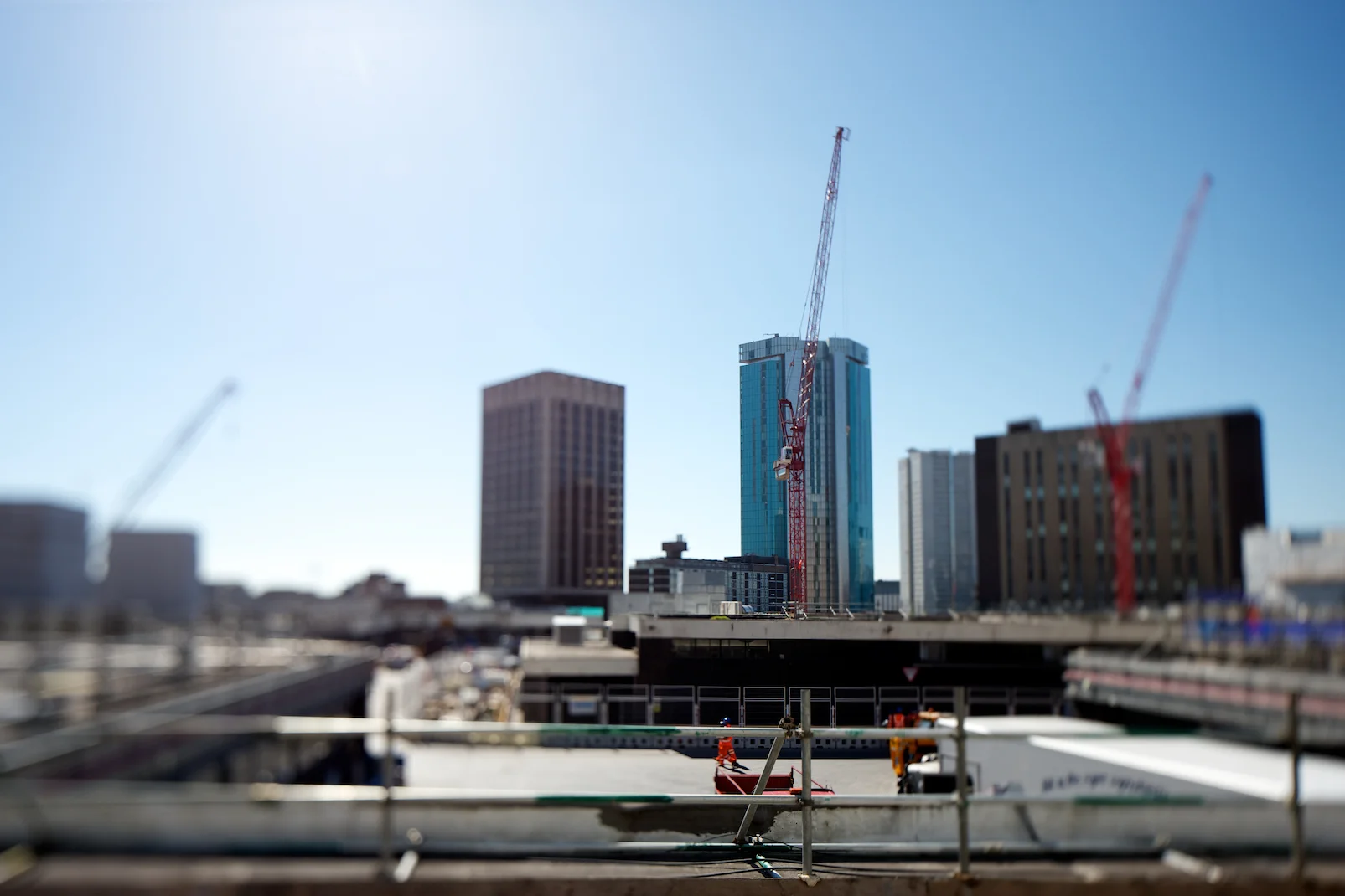 Construction site with cranes and high-rise buildings in the background on a sunny day.