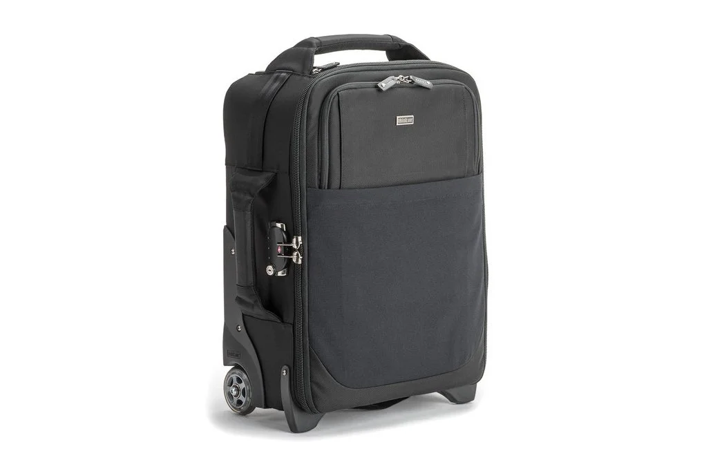 Black rolling carry-on suitcase with front pocket, handle, and wheels, isolated on white background.